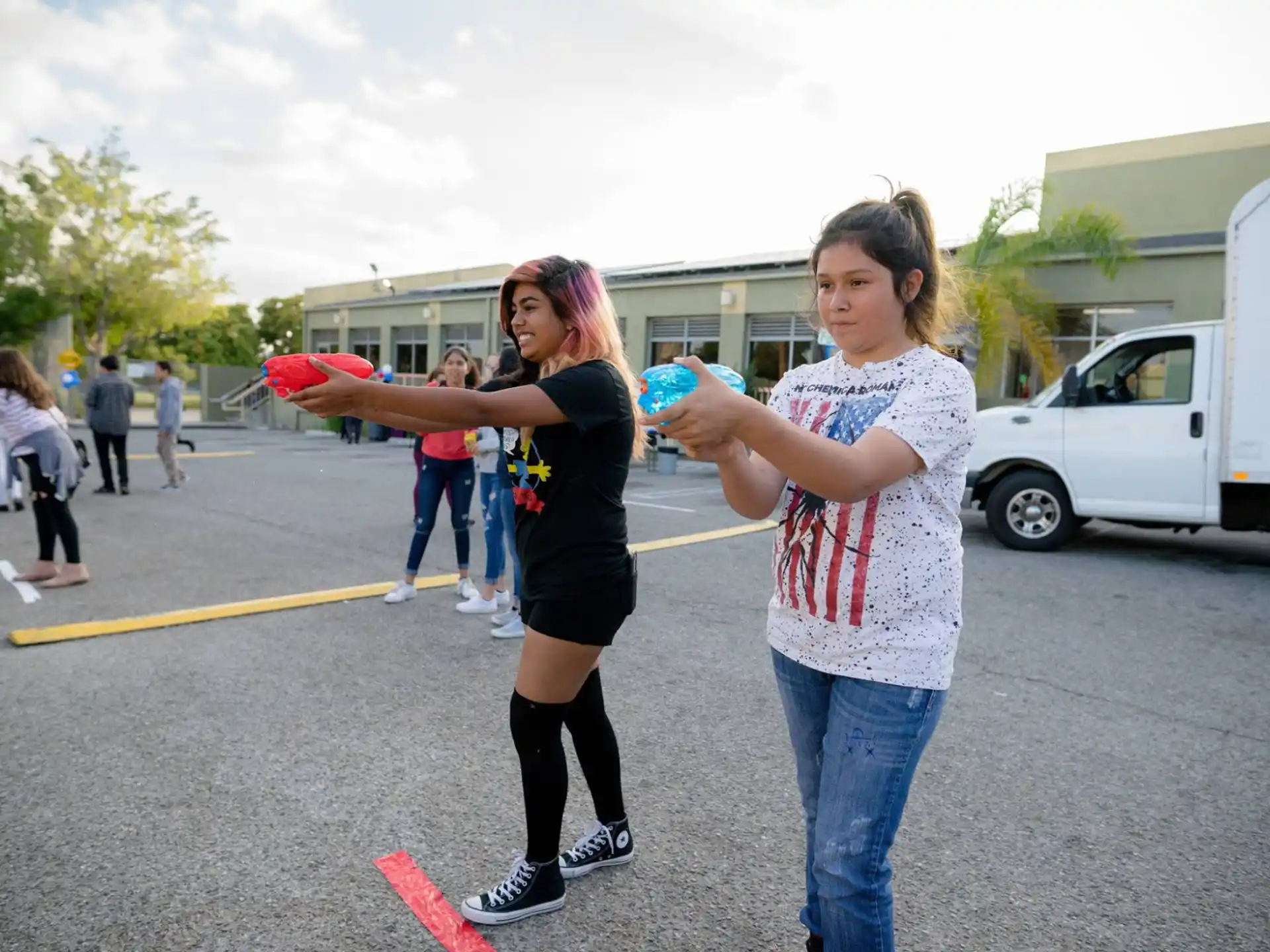 a couple of girls holding frisbees in a parking lot