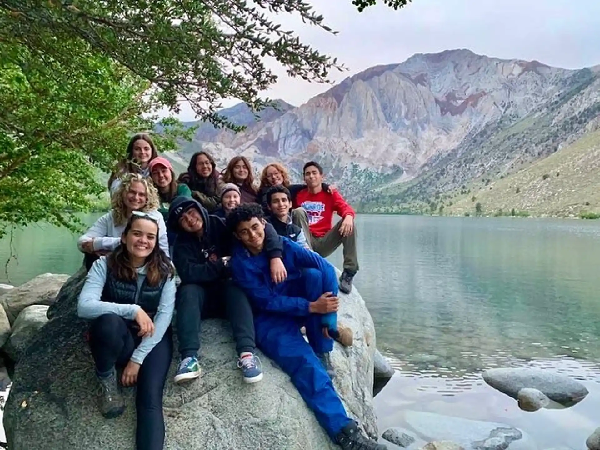 a group of people sitting on a rock by a lake