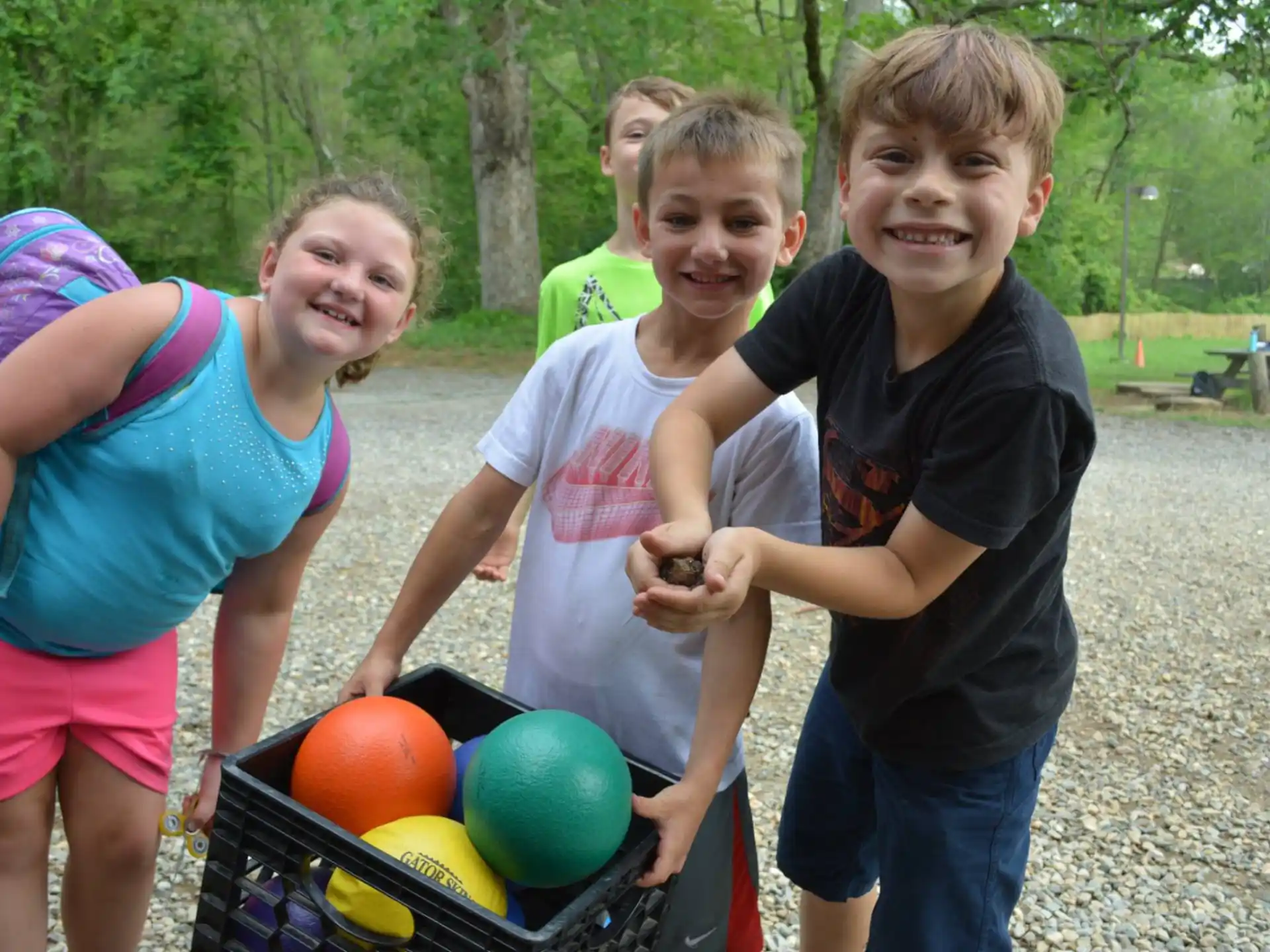 a group of children holding a basket of balls