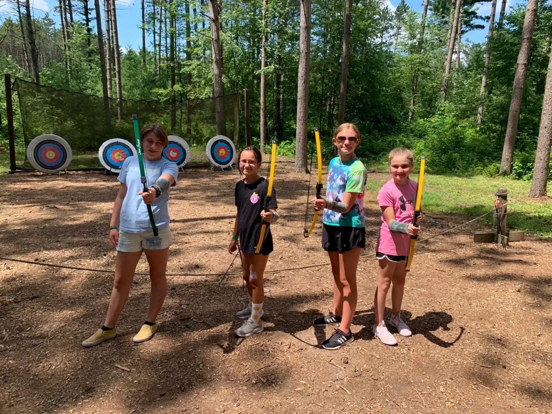 a group of people holding bows and arrows in a forest