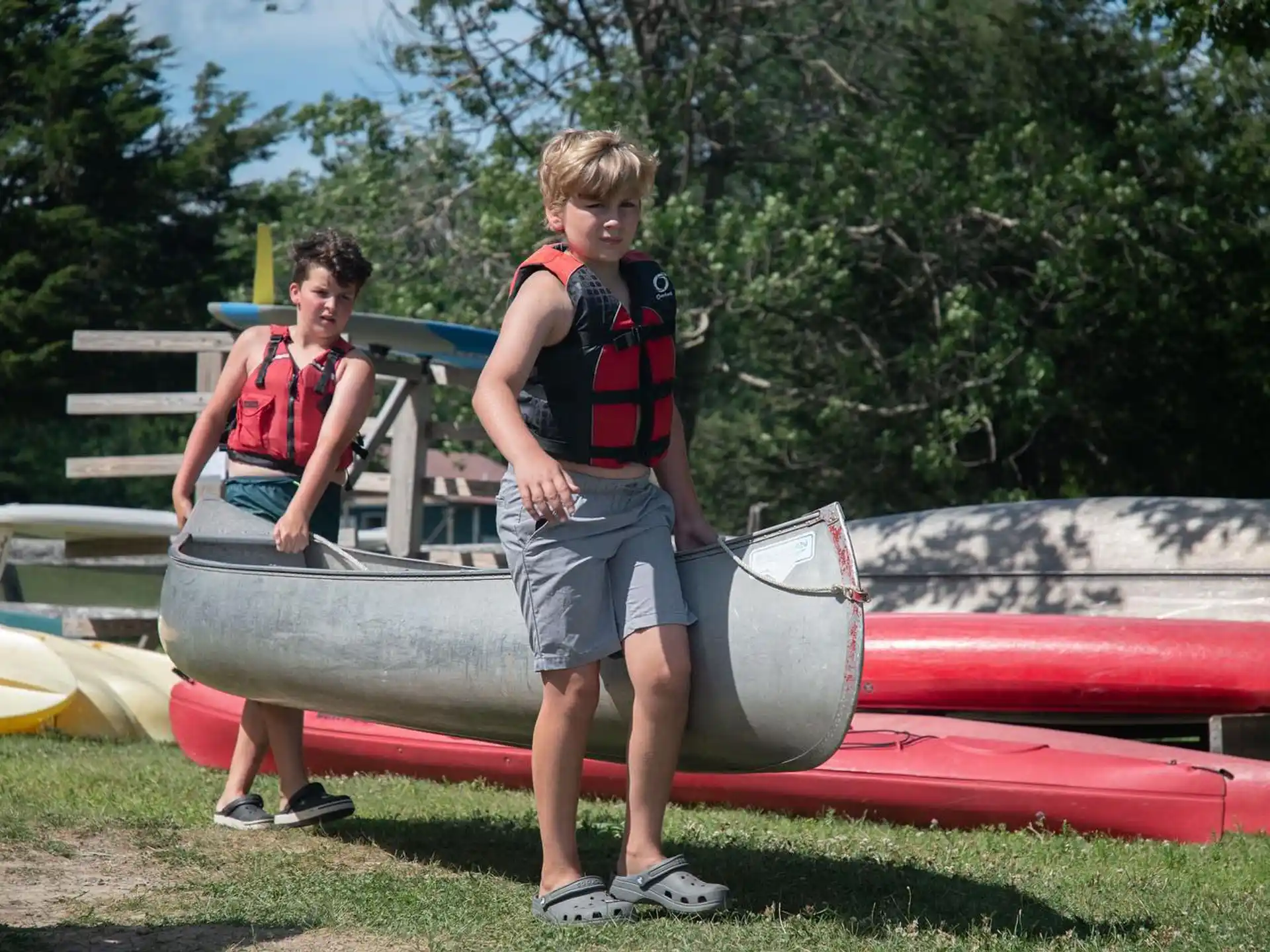 a couple of boys standing next to a boat