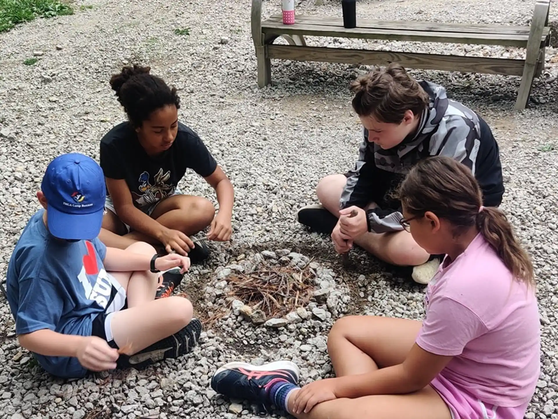 a group of people sitting on the ground looking at a small animal