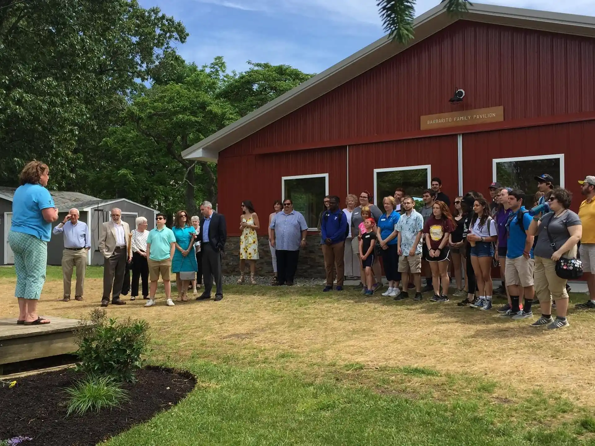 a group of people posing for a photo in front of a red barn