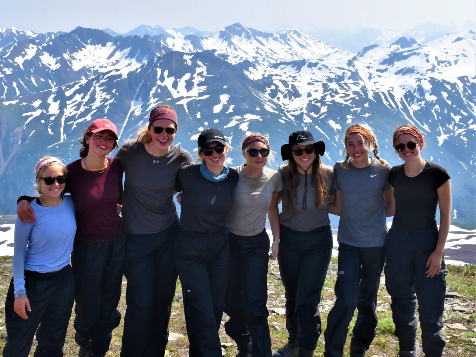 a group of people posing for a photo in front of a snowy mountain