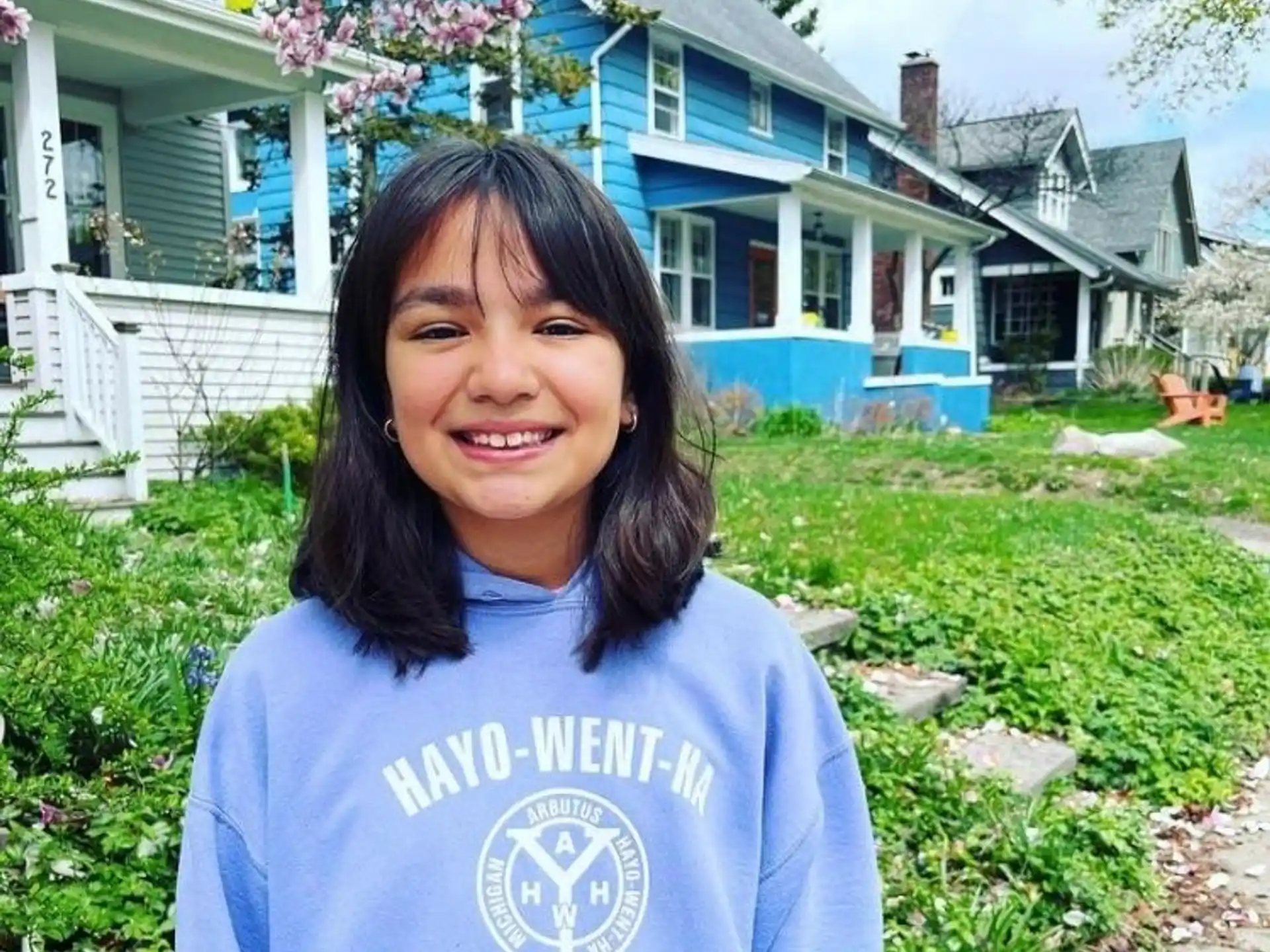 a person smiling in front of a house