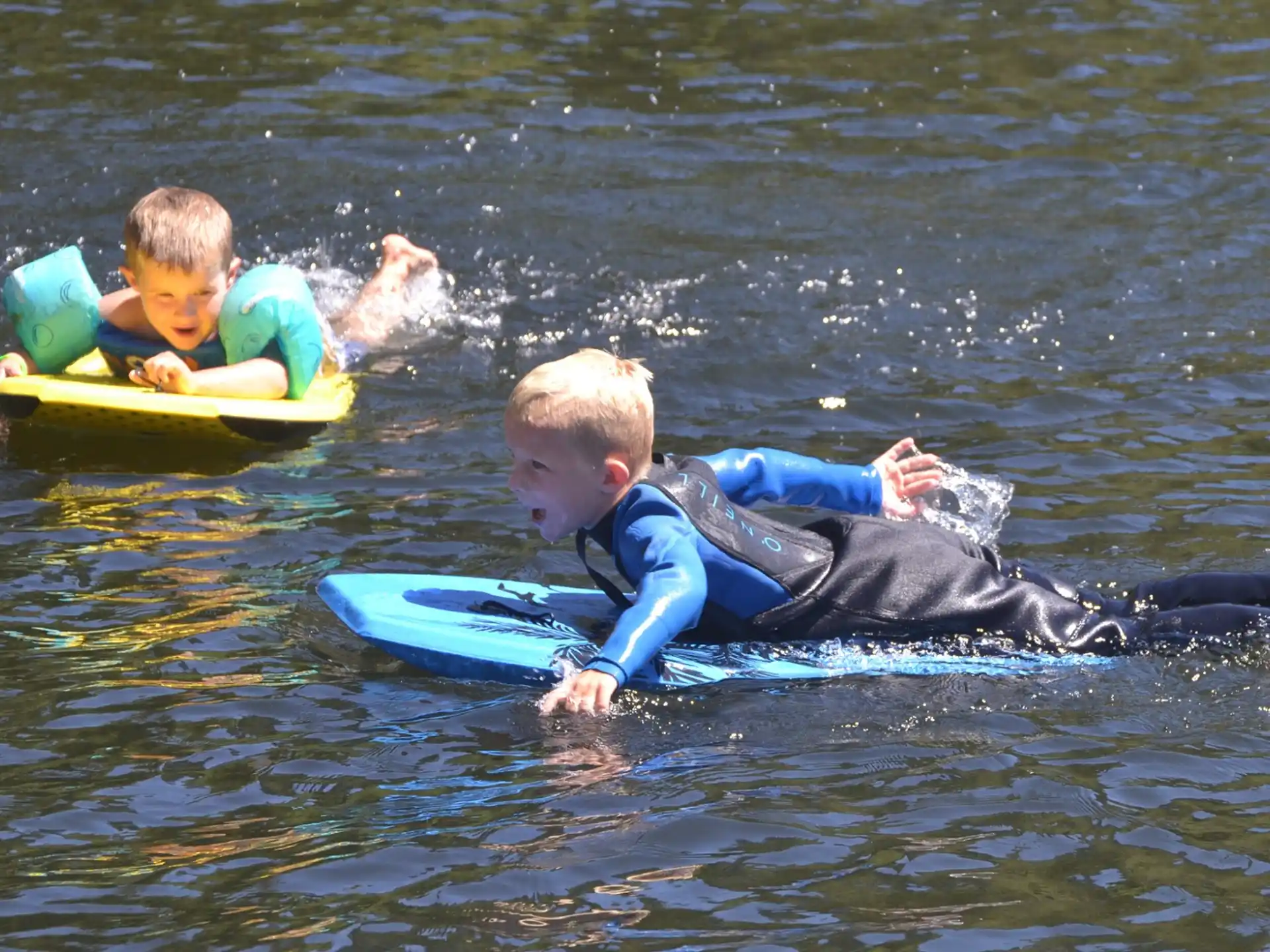 a couple of boys on a floating raft in the water