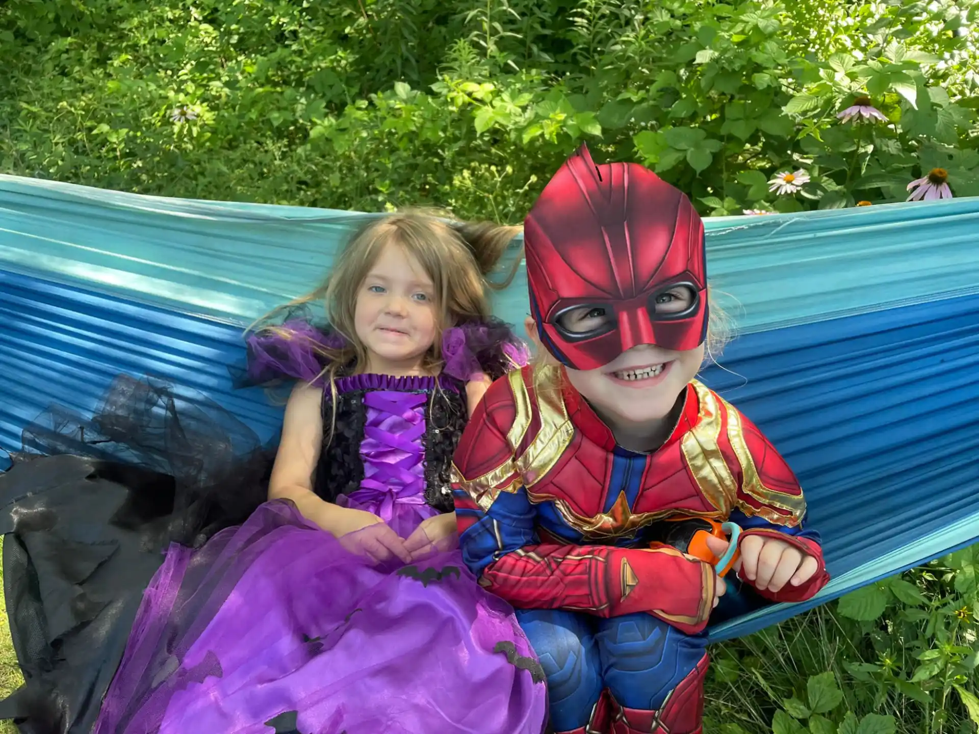 a couple of children sitting on a bench wearing clothing