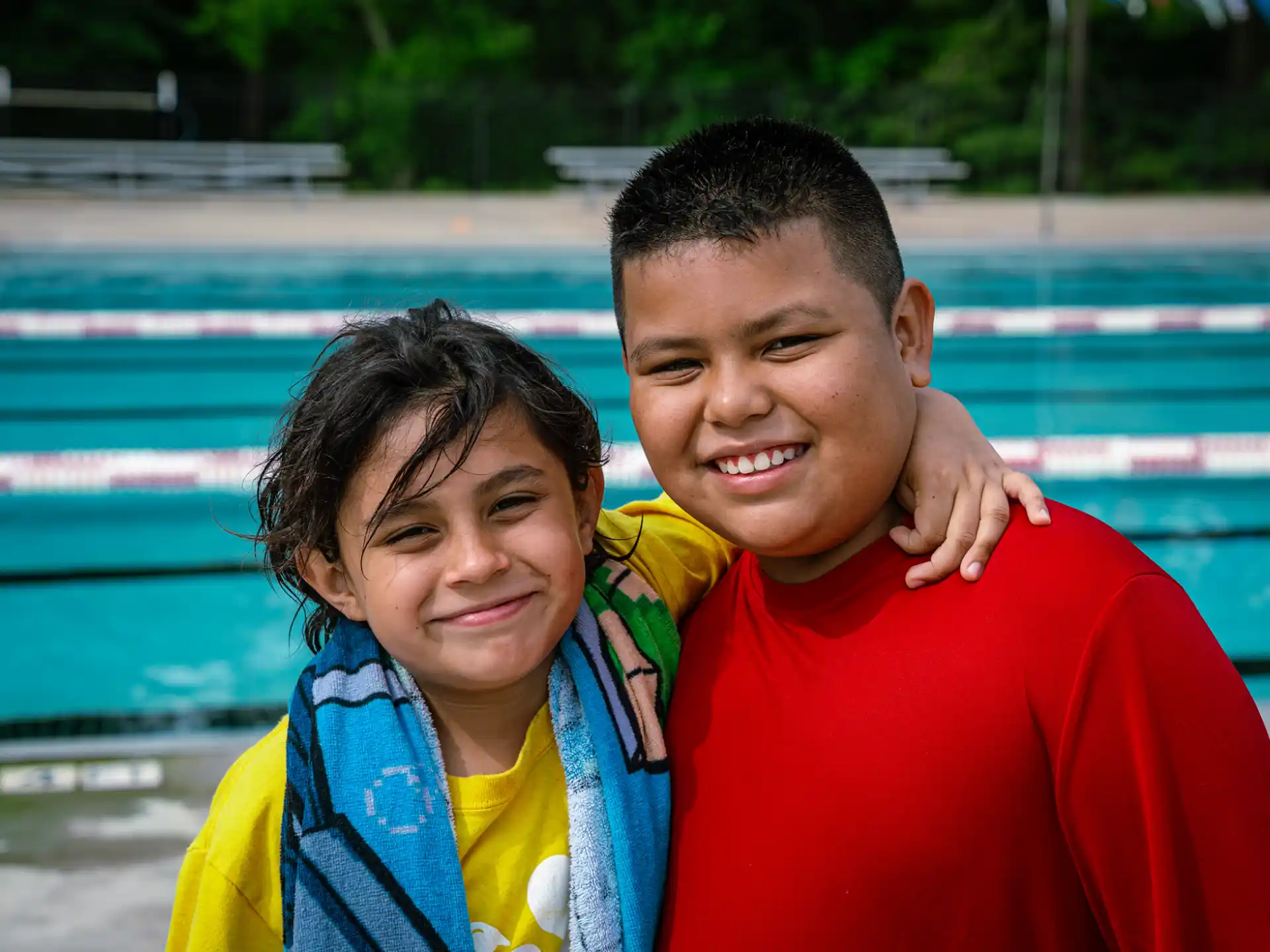 a boy and girl posing for a picture next to a pool