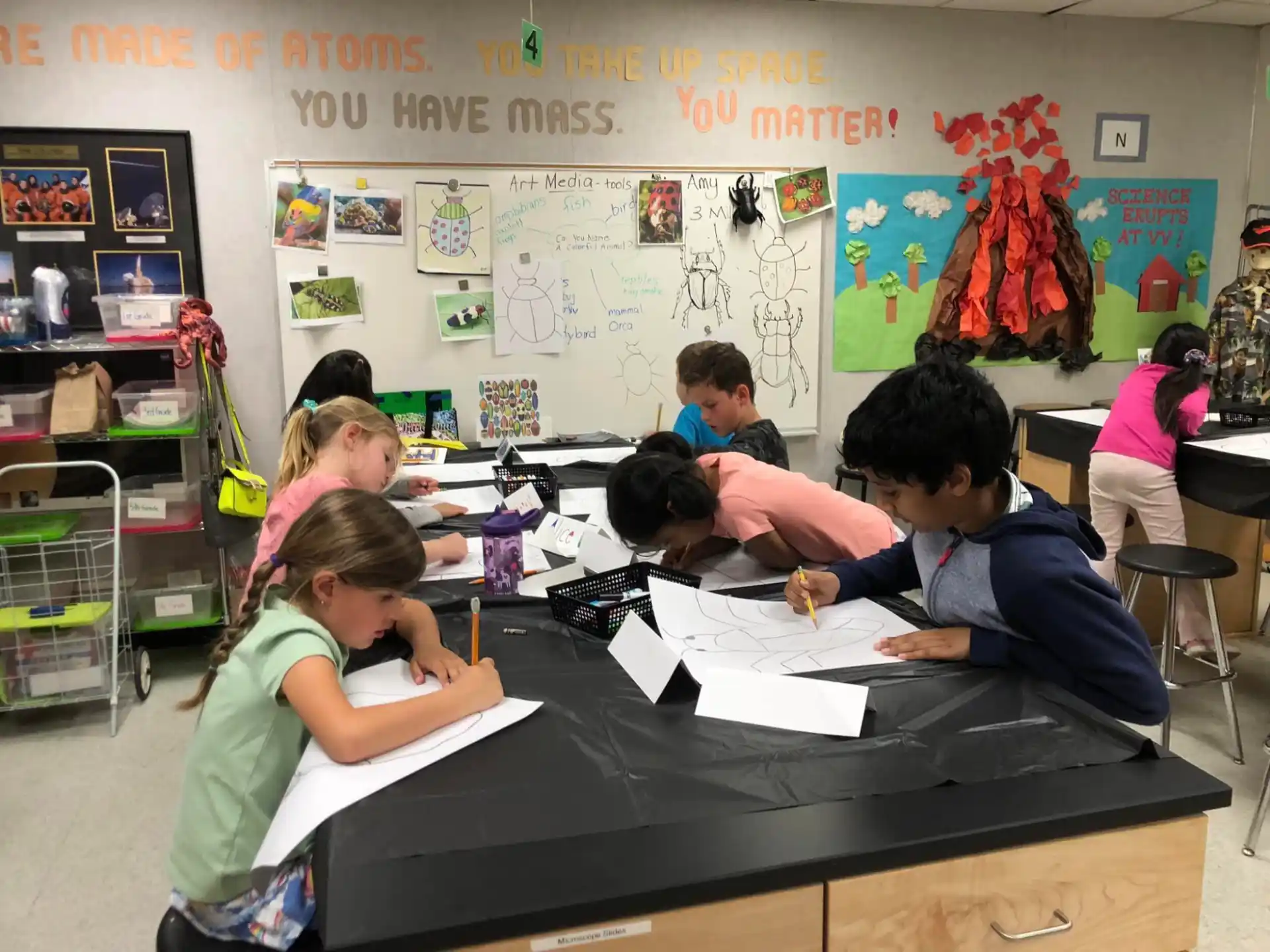 a group of children sitting at a table in a classroom