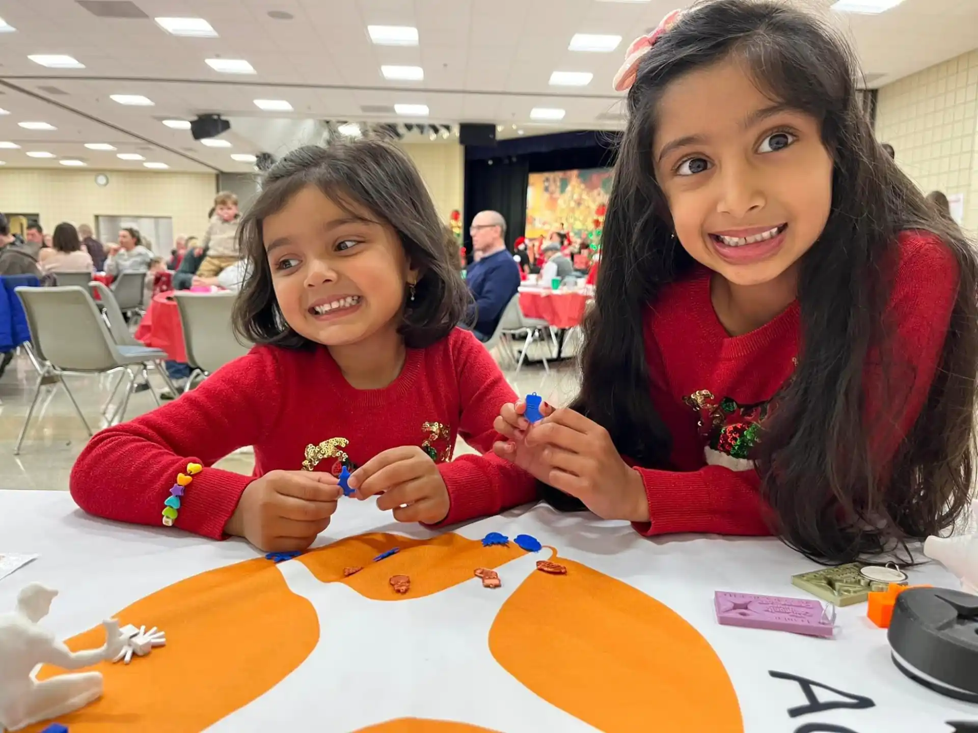 a couple of girls sitting at a table with colorful paper on it