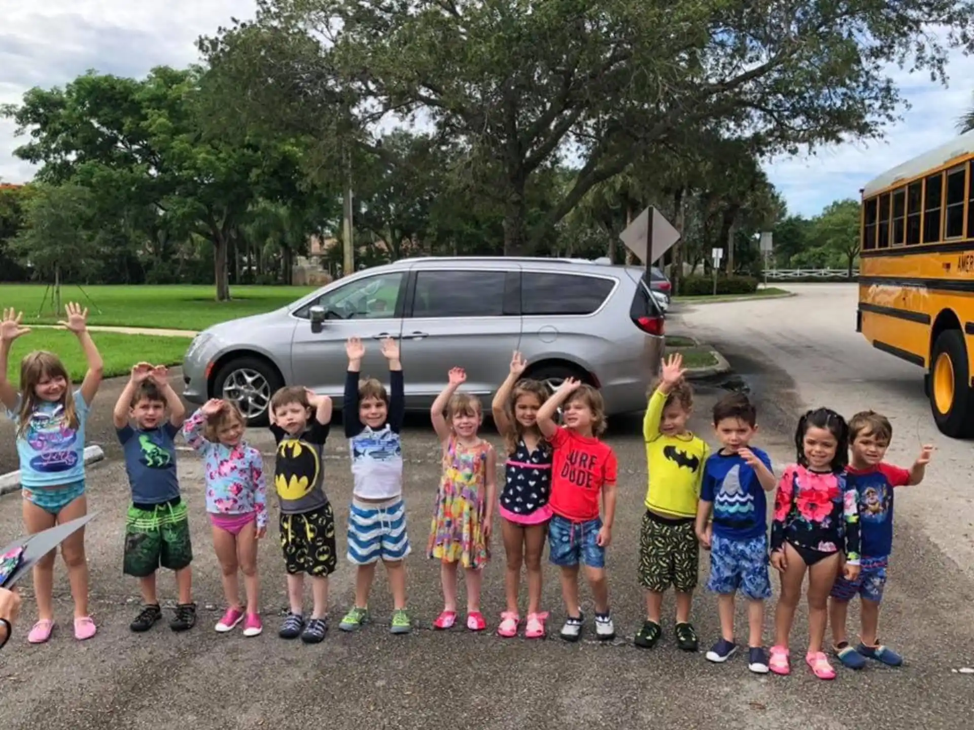 a group of children posing for a photo in front of a car