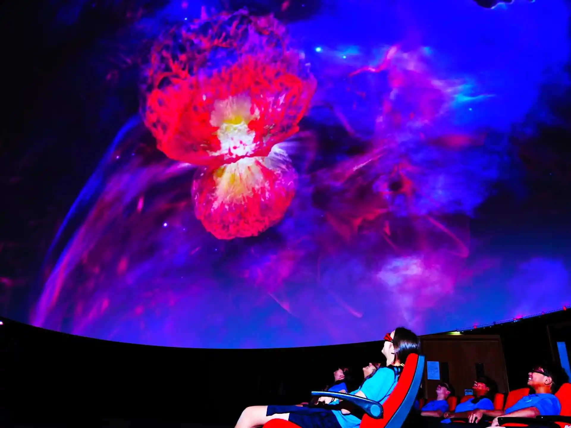 a group of people sitting in chairs with a large pink and blue balloon in the sky