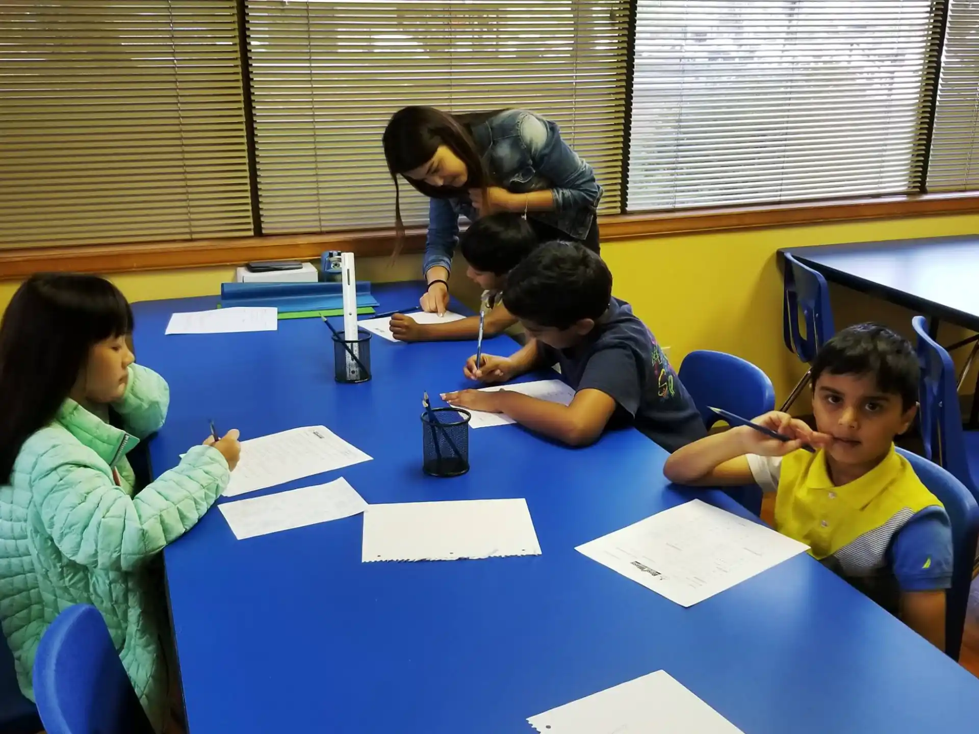 a group of children sitting at a table writing on paper