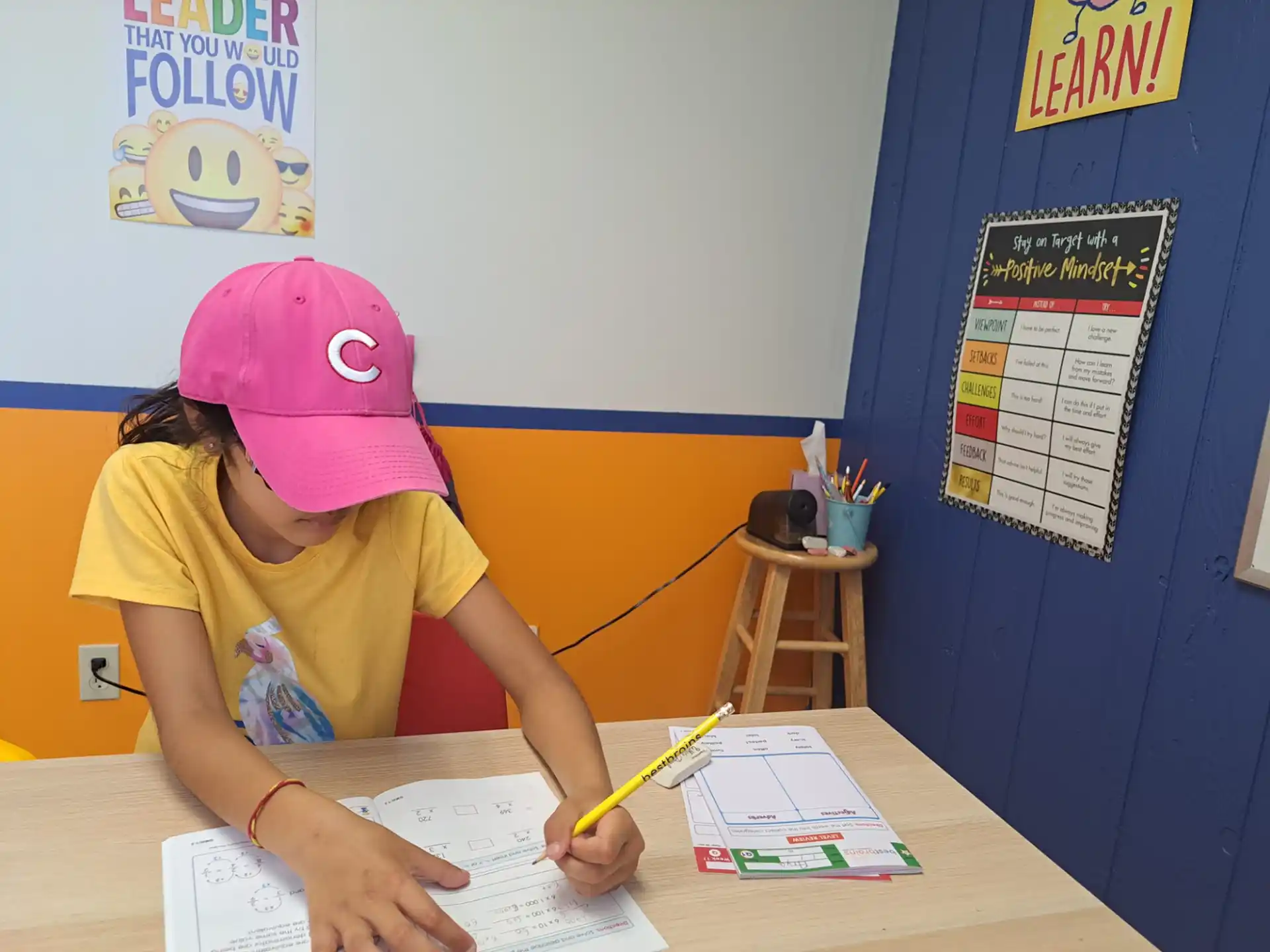 a girl sitting at a desk writing on a piece of paper