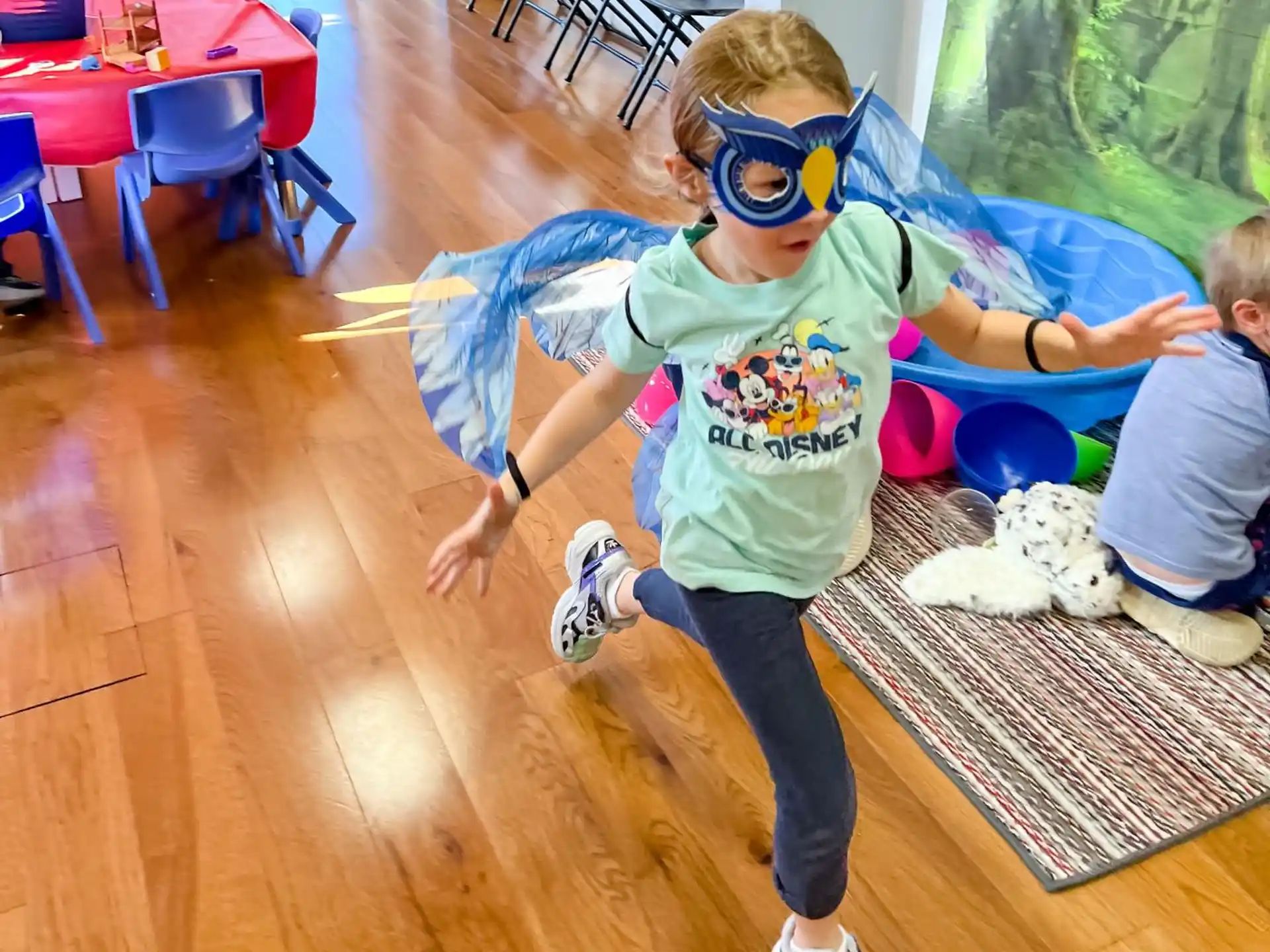 a girl wearing a mask and dancing with a boy in a room with tables and chairs