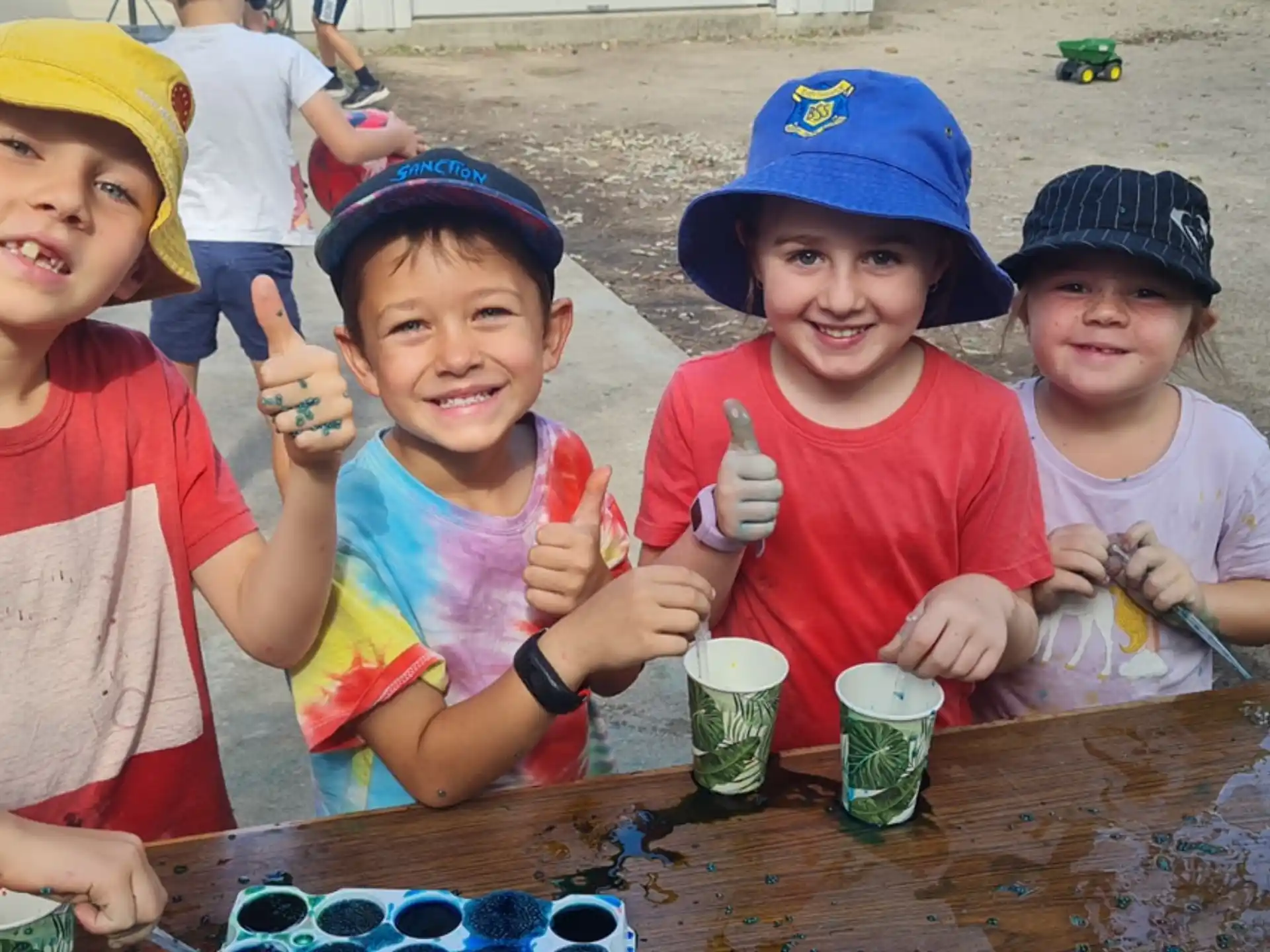 a group of kids sitting at a table with food and drinks