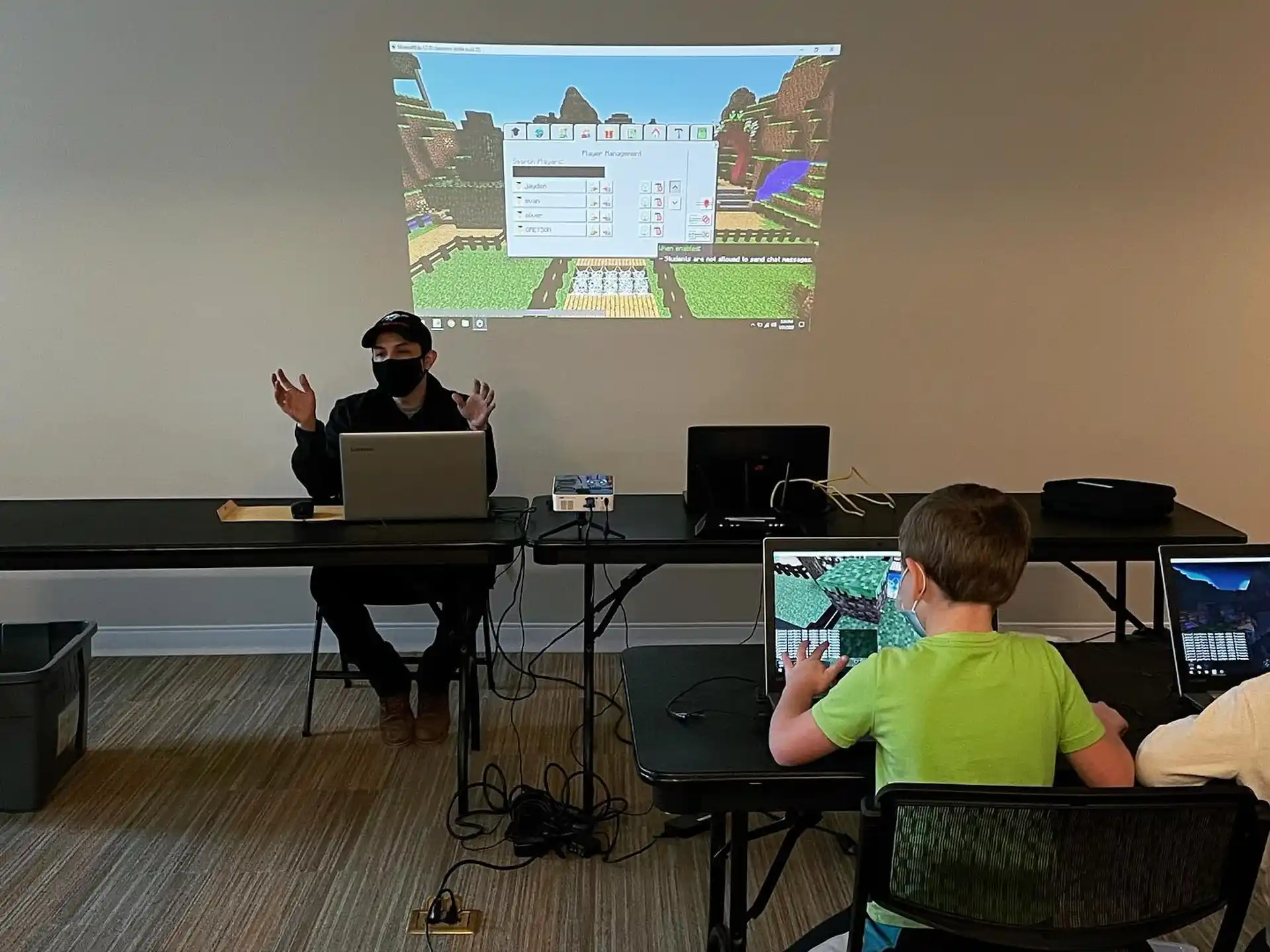 a person and a boy sitting at a desk with computers