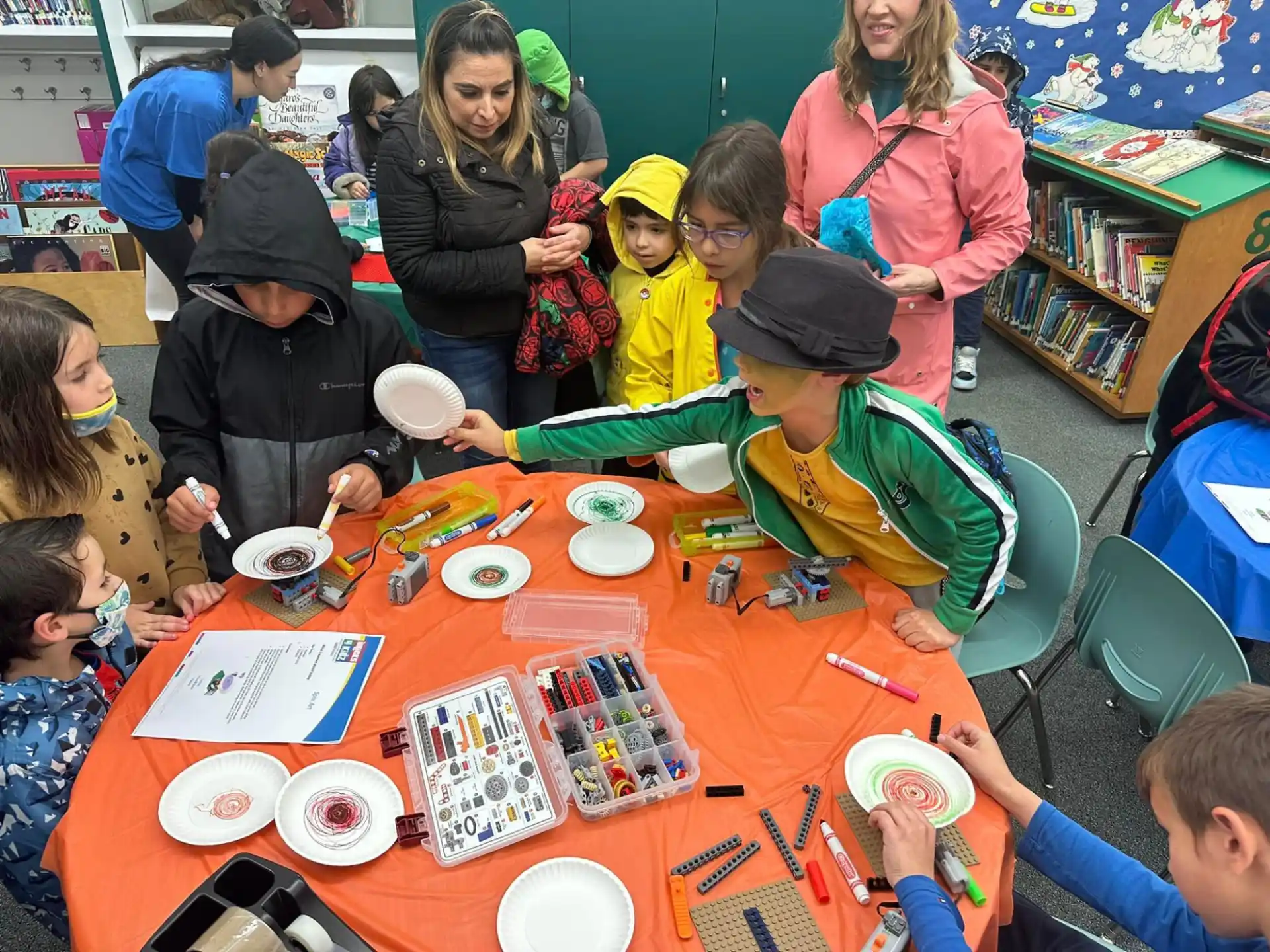 a group of children sitting around a table with food and drinks