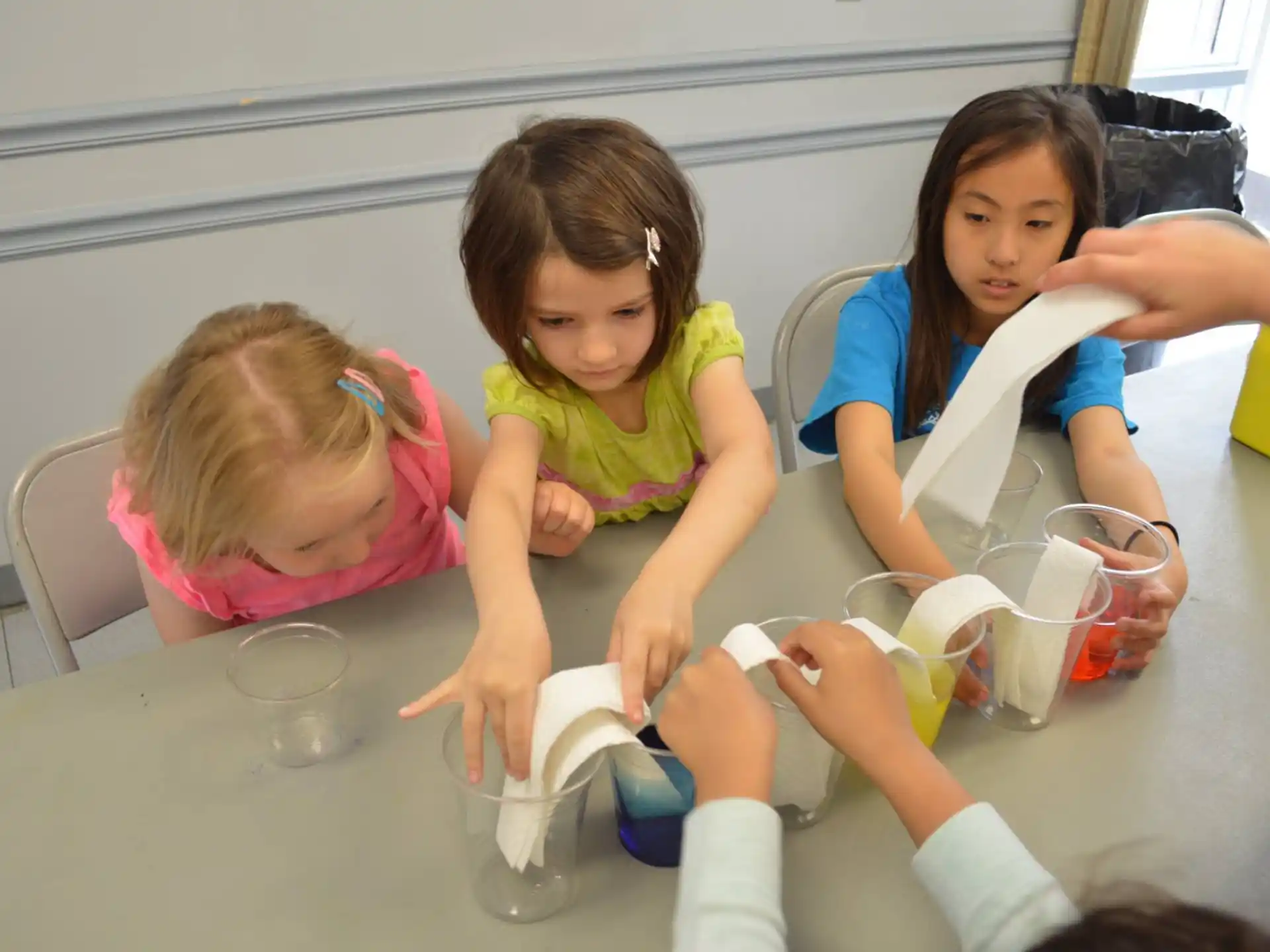 a group of girls sitting at a table with cups and a plate of food