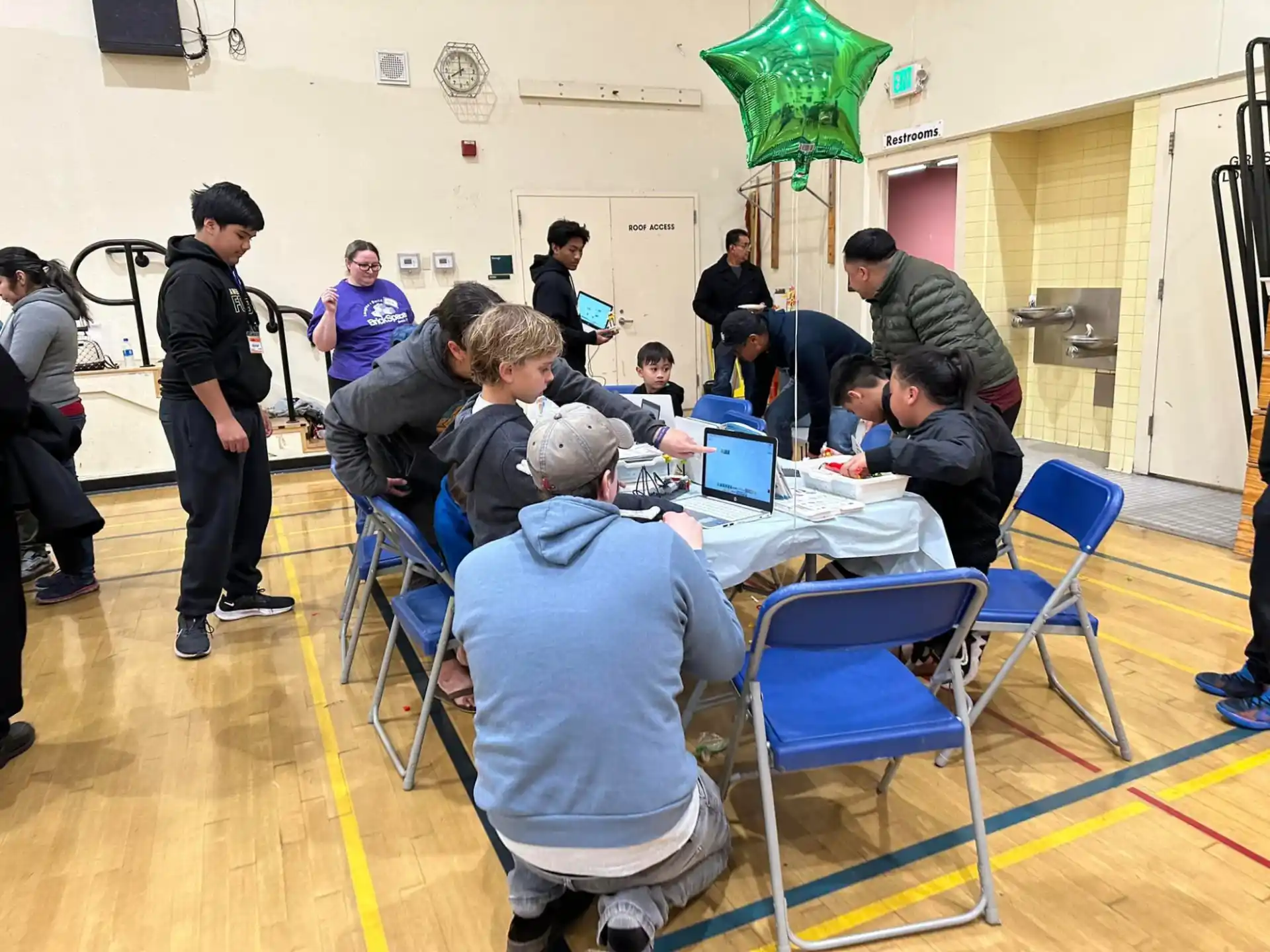 a group of people sitting around a table with laptops