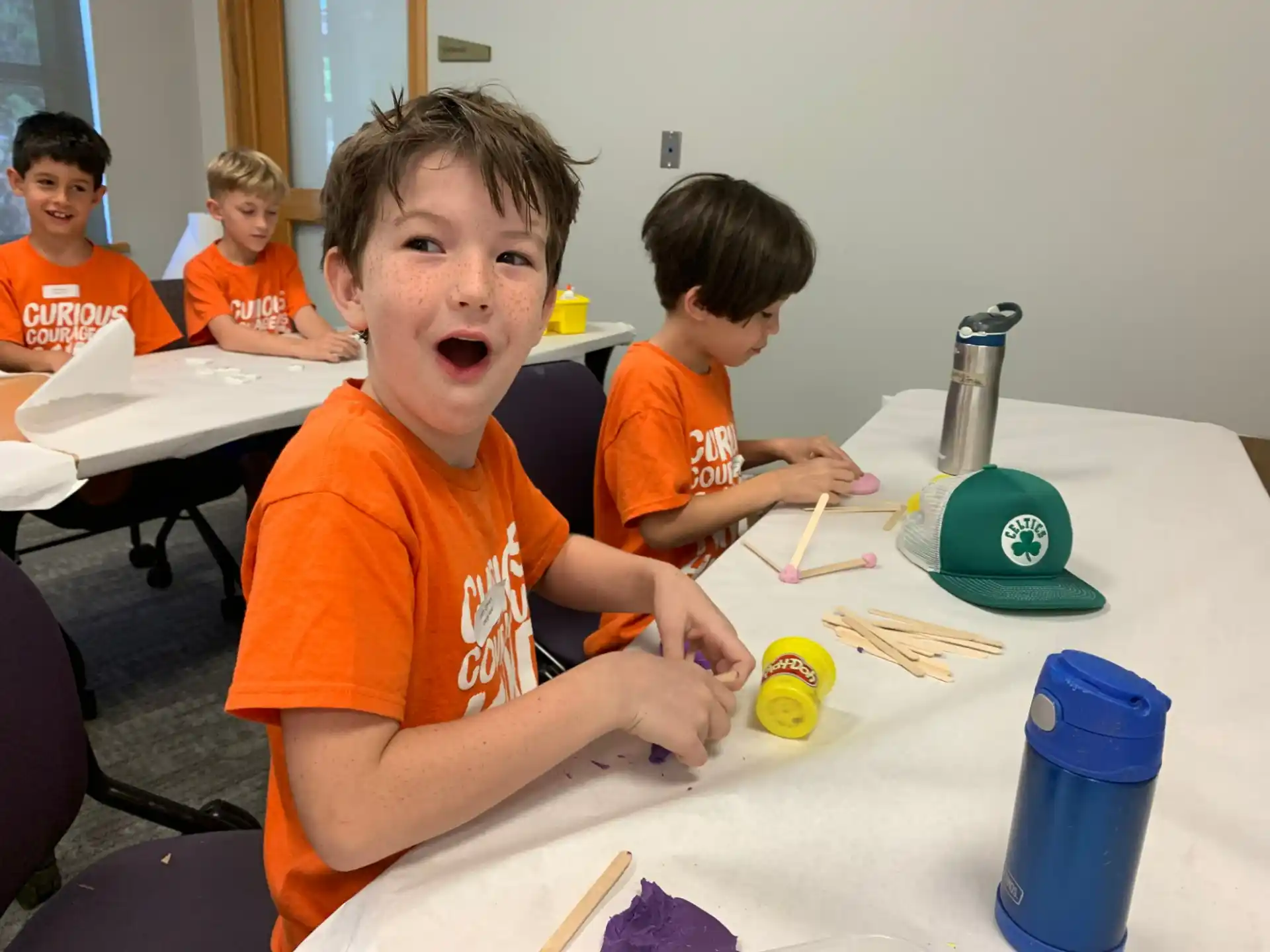 a group of kids sitting at a table with paint brushes
