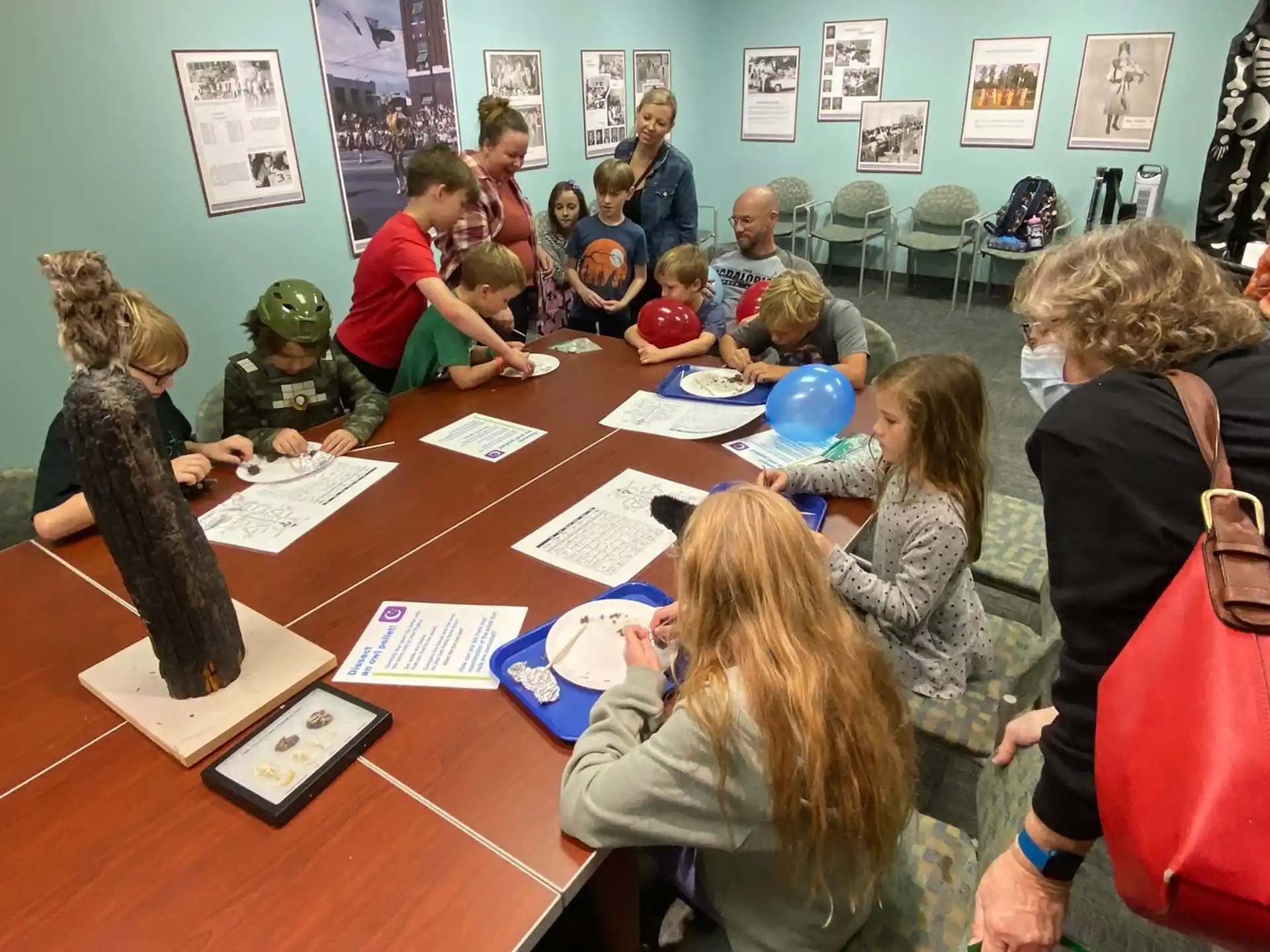 a group of people sitting at a table with stuffed animals