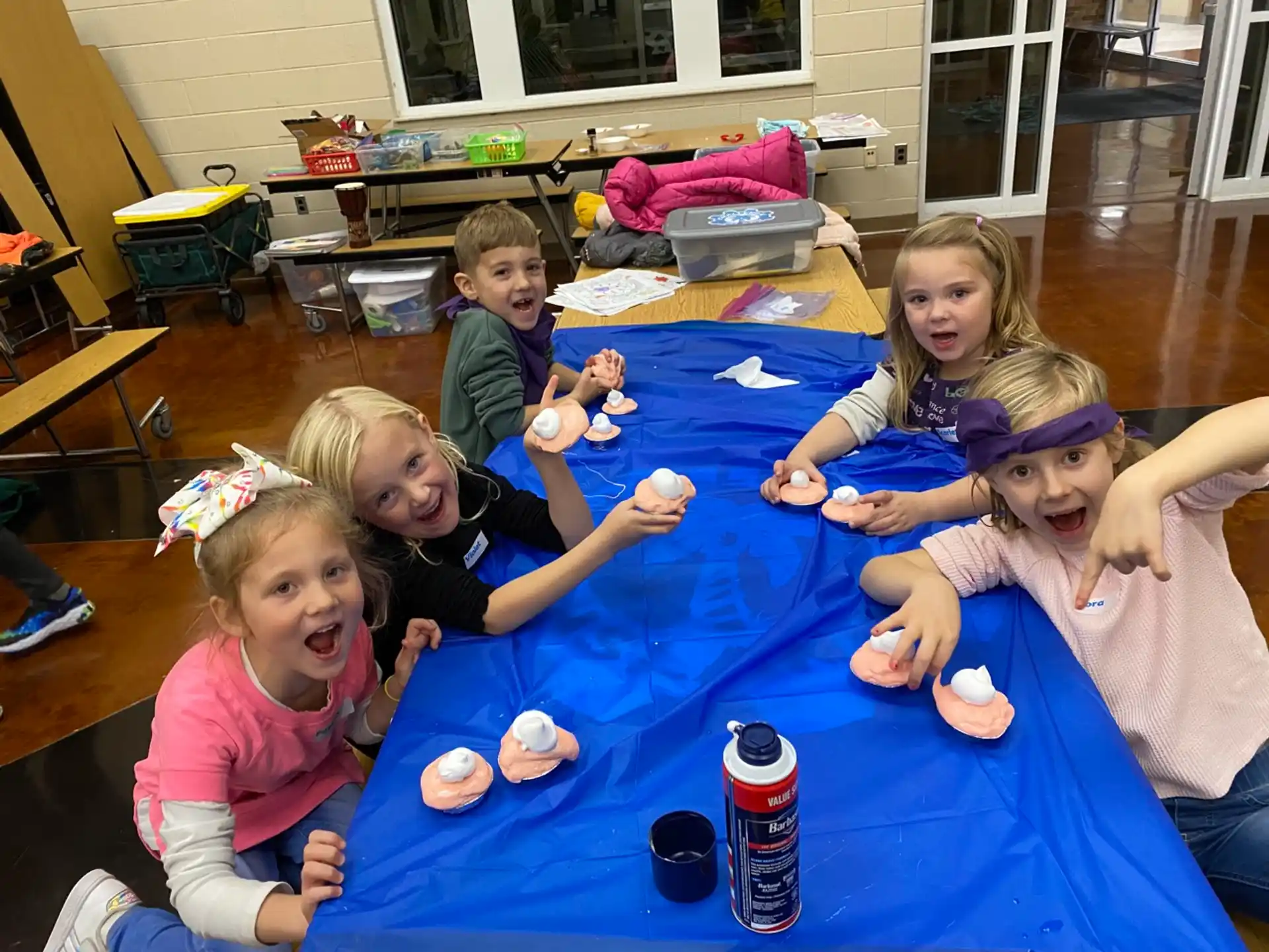 a group of children sitting on a blue mat with a blue tablecloth