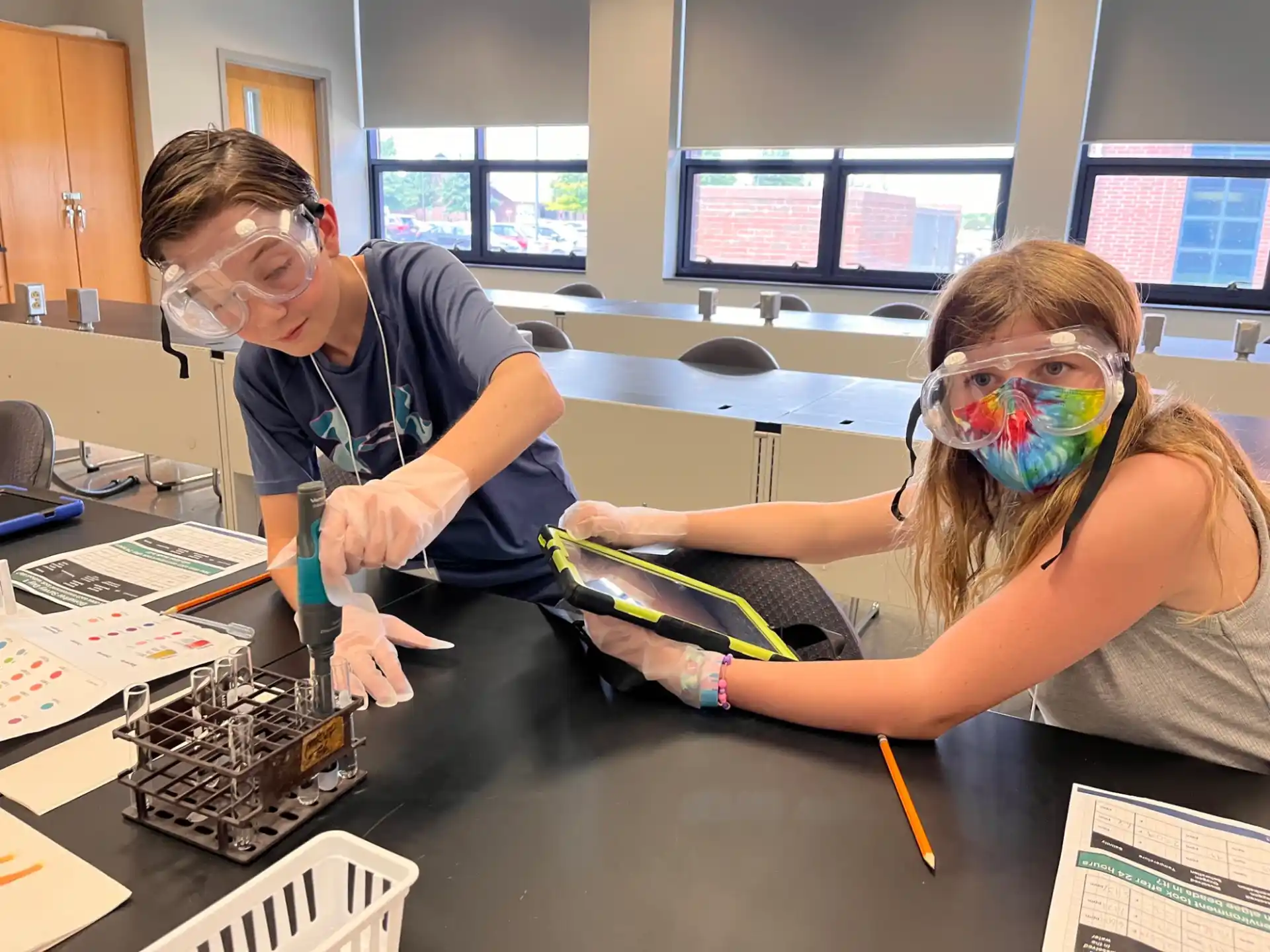 a man and a woman wearing safety goggles working on a machine