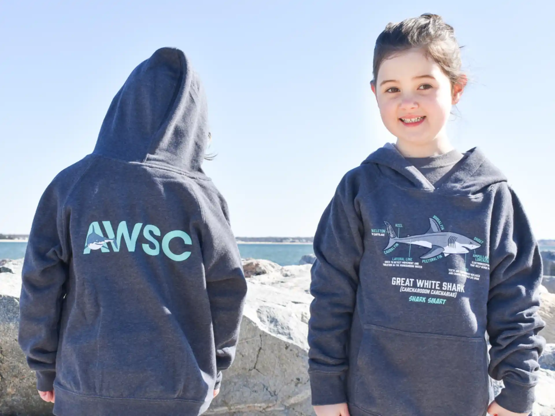 a boy and a girl standing on a rocky beach