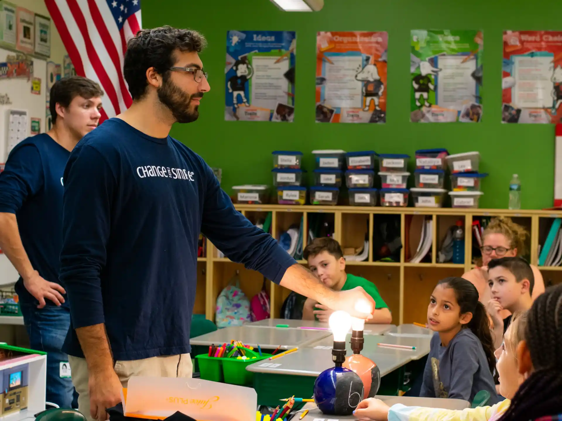 a person standing in front of a classroom with a group of children