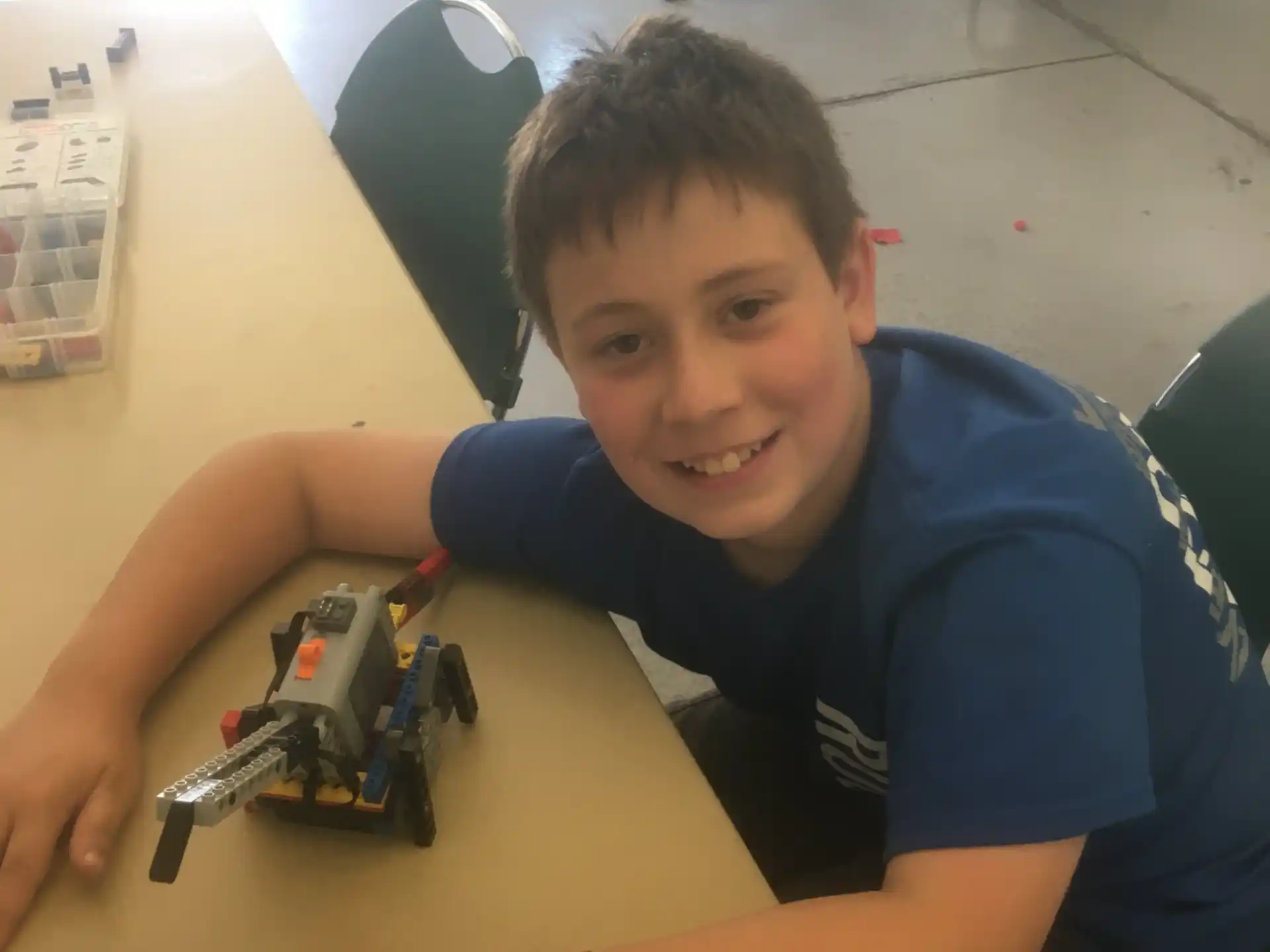 a boy sitting at a table with a toy car