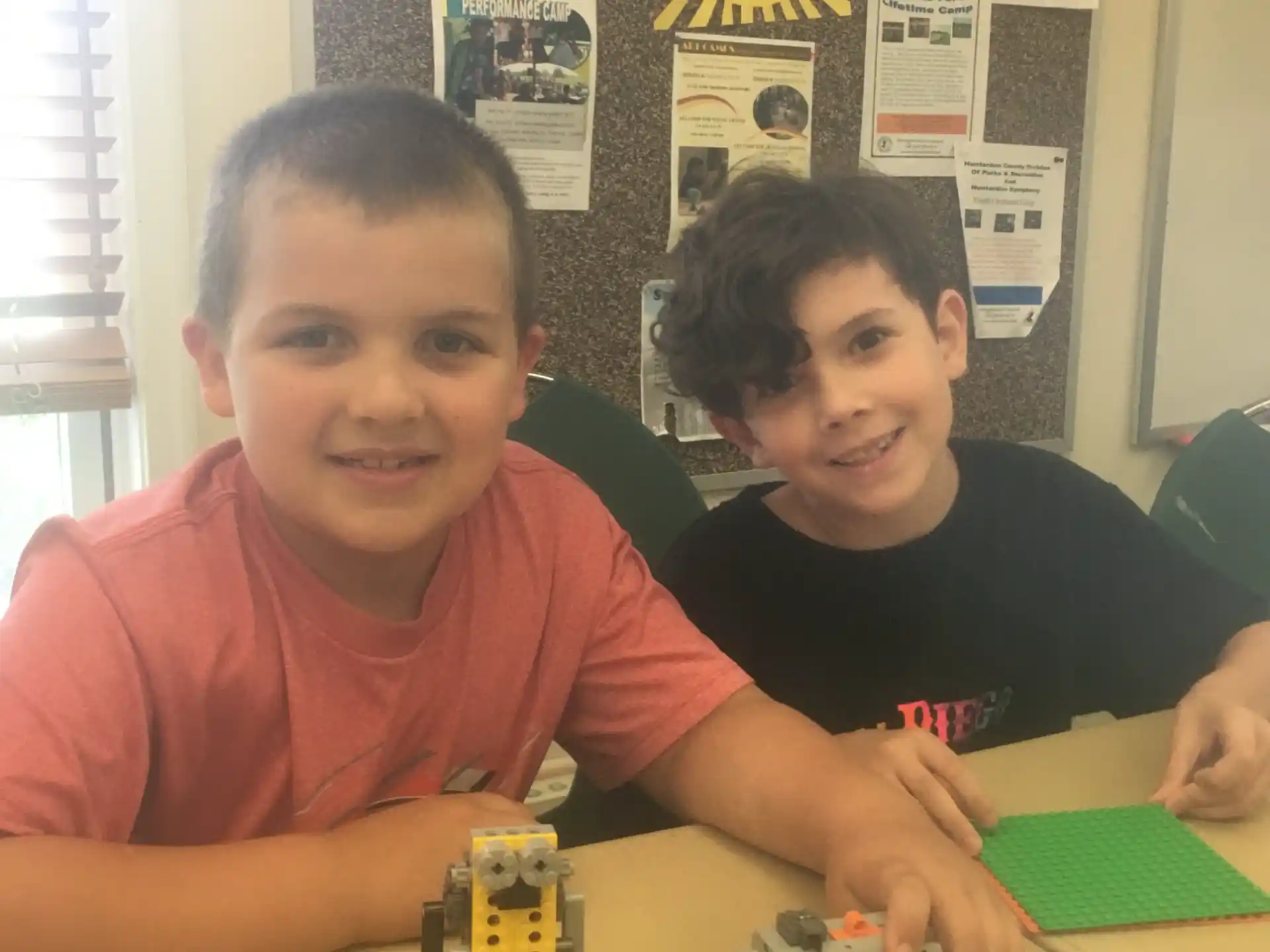 a couple of boys sitting at a table with toy trains