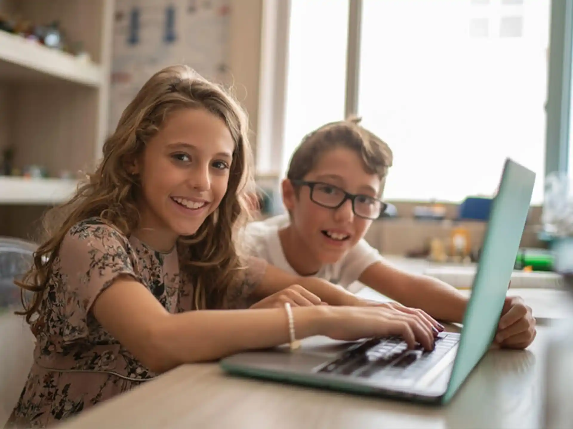 a boy and girl looking at a laptop