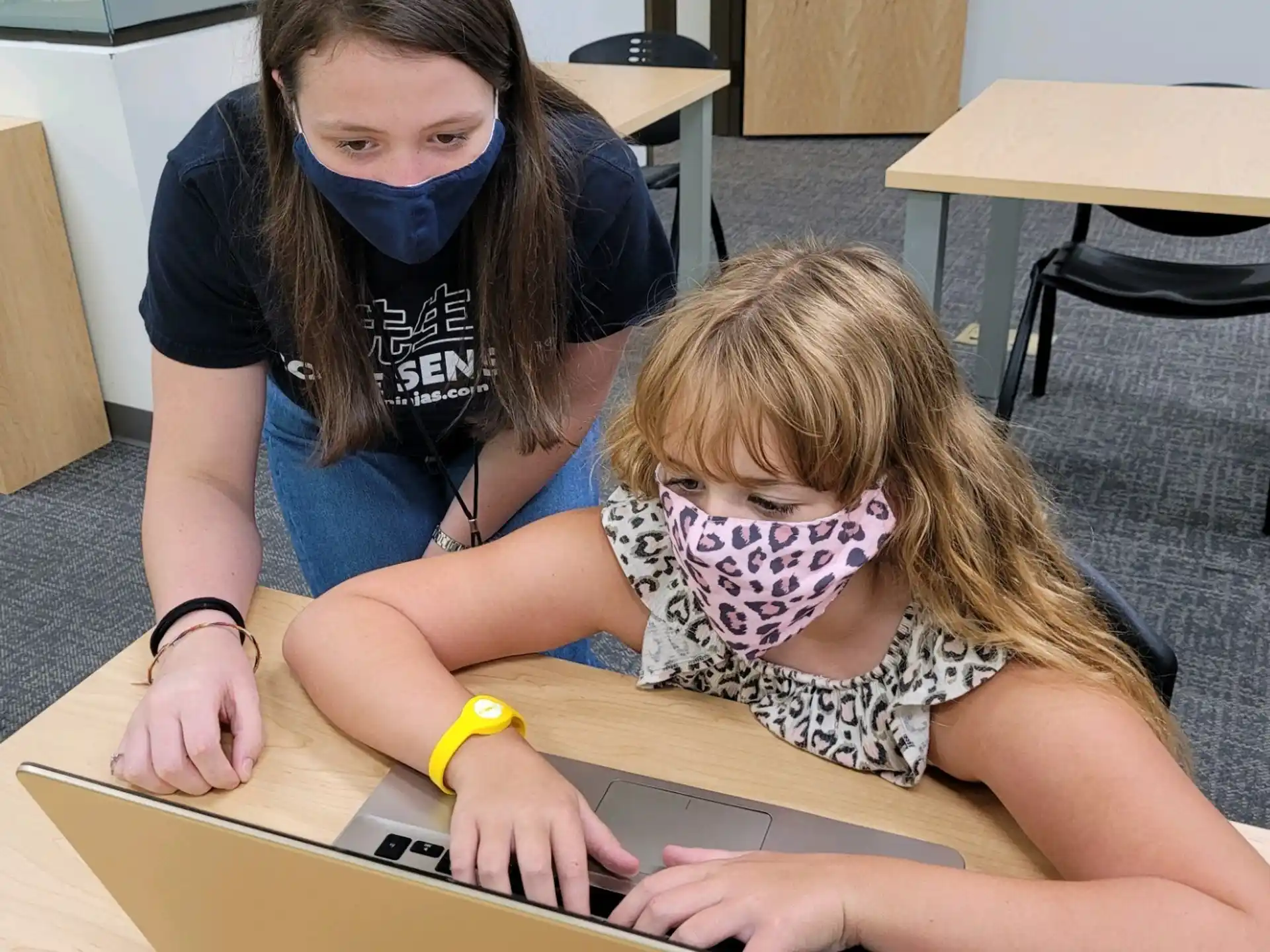 a person and a girl looking at a laptop