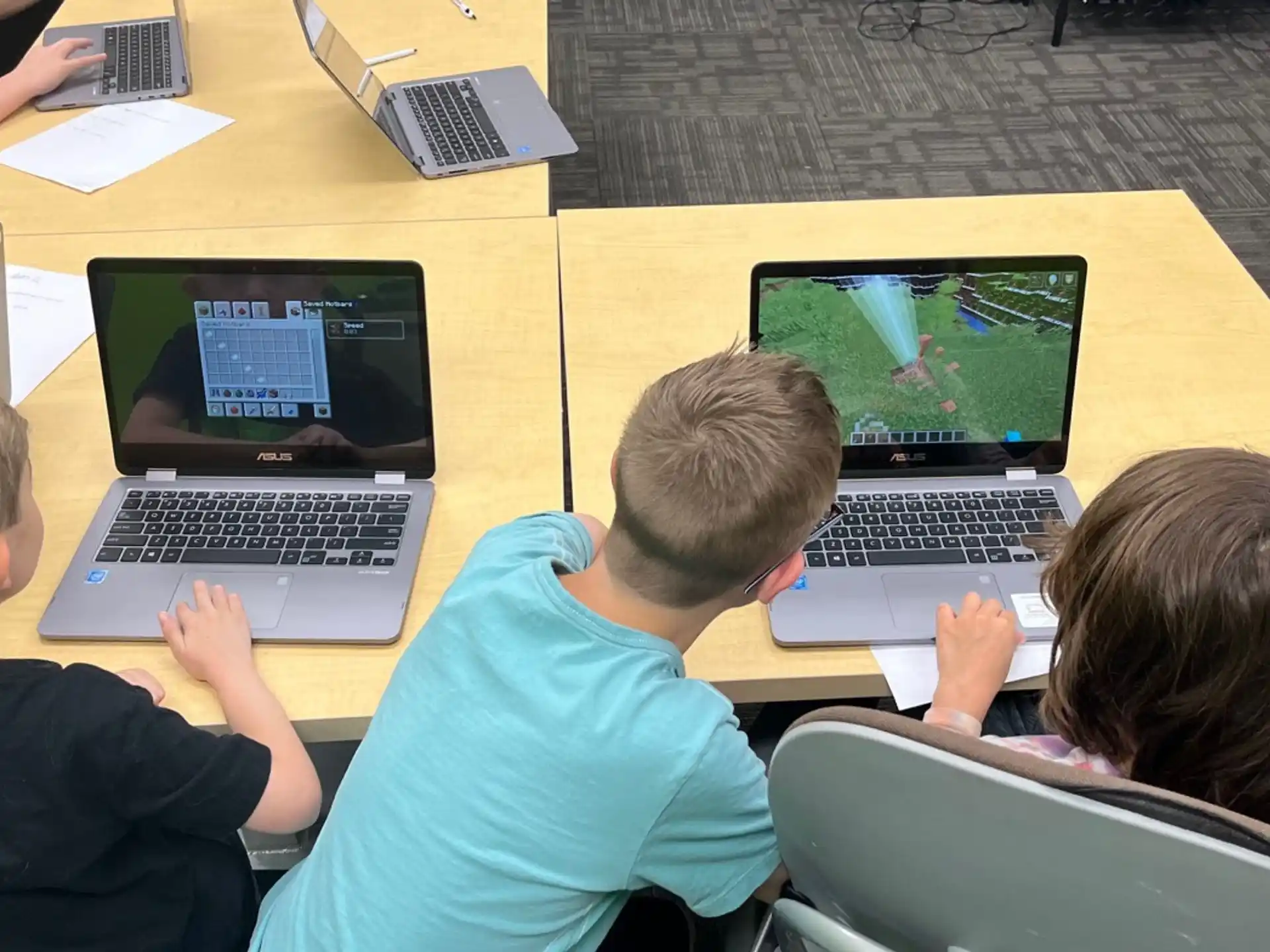 a group of people sitting at a table with laptops