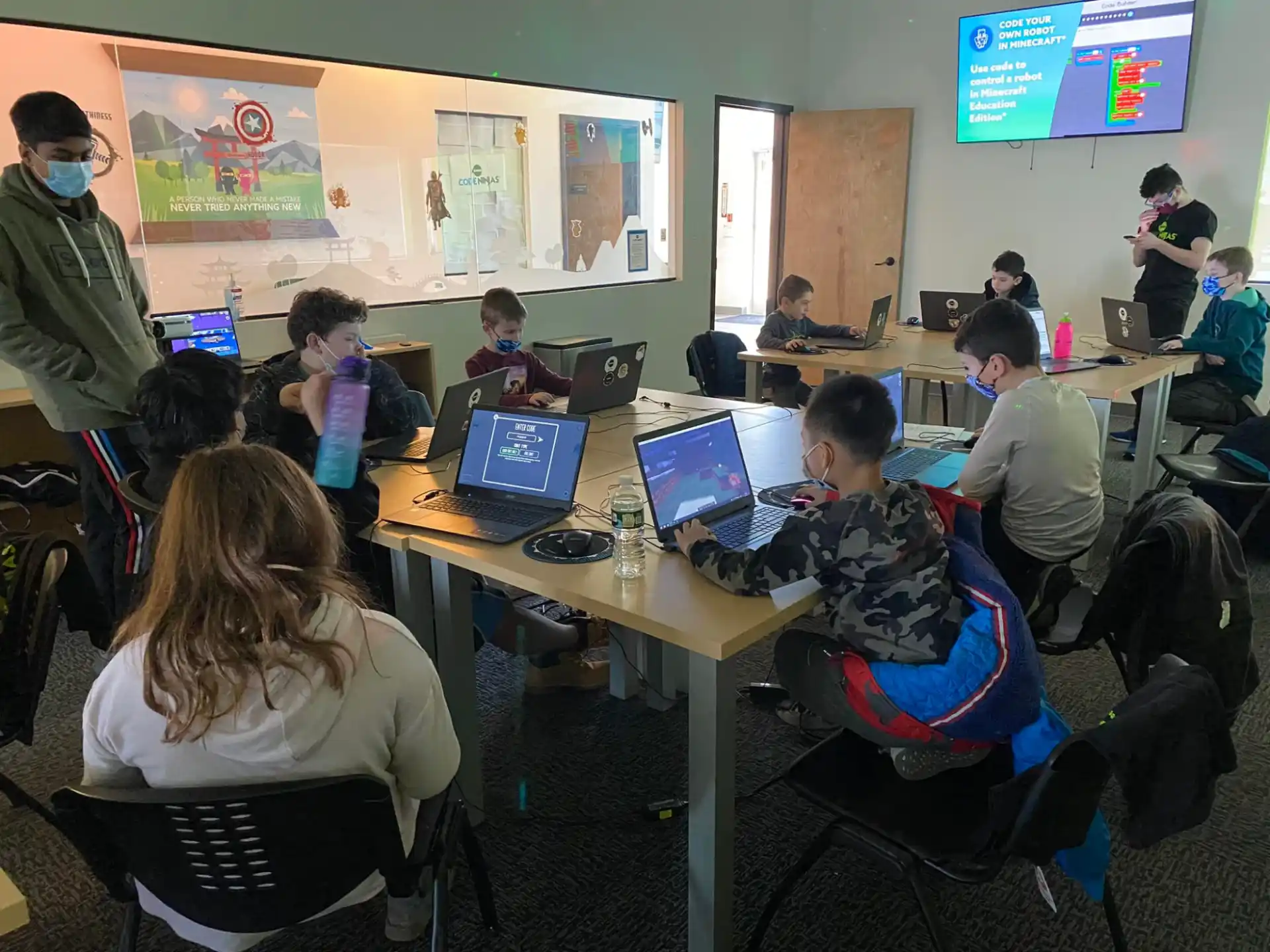 a group of people sitting at desks with laptops
