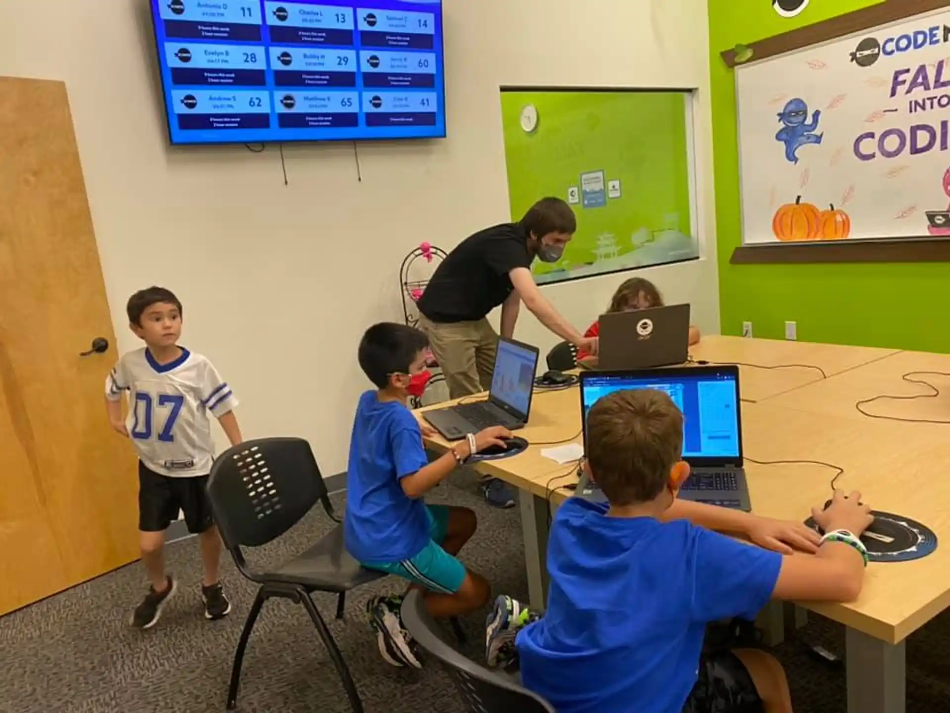 a group of kids sitting at a table with laptops
