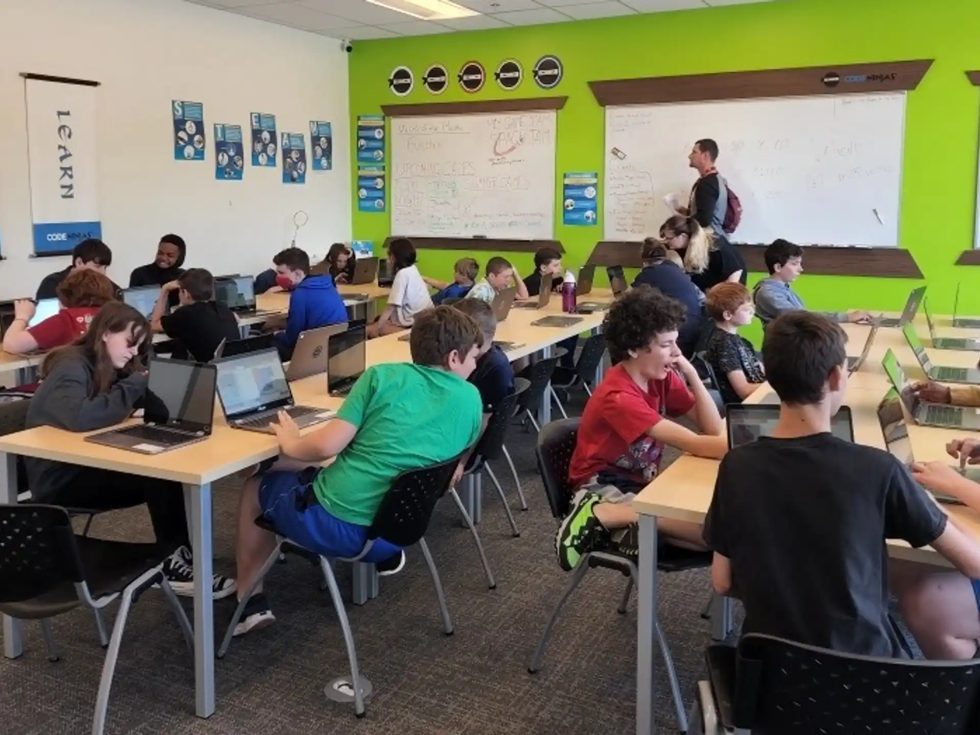 a group of people sitting at tables with laptops