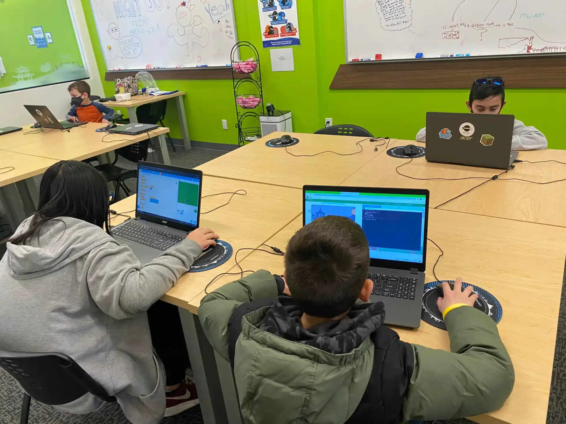 a group of people sitting at a table with laptops