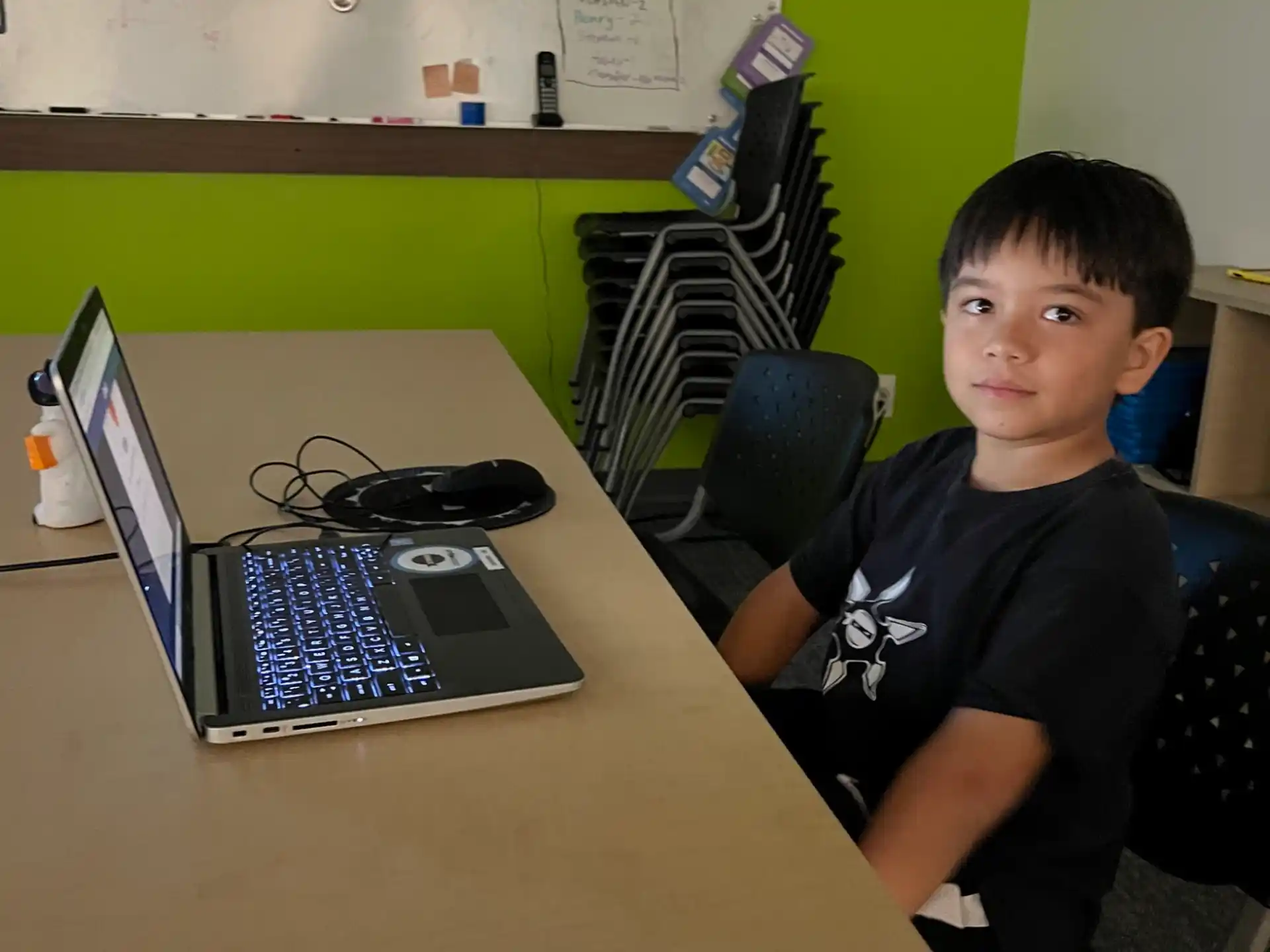 a boy sitting at a desk with a laptop