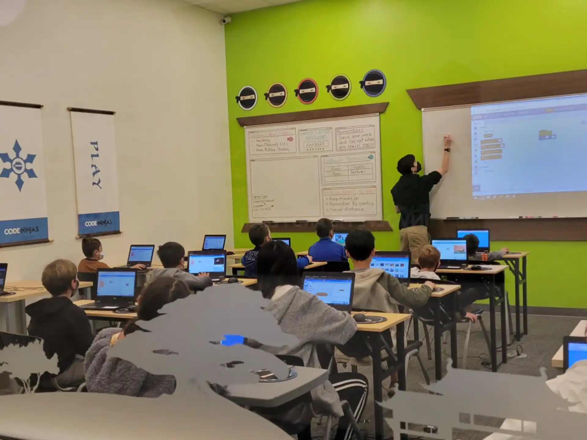 a classroom with people sitting at desks and a projection screen