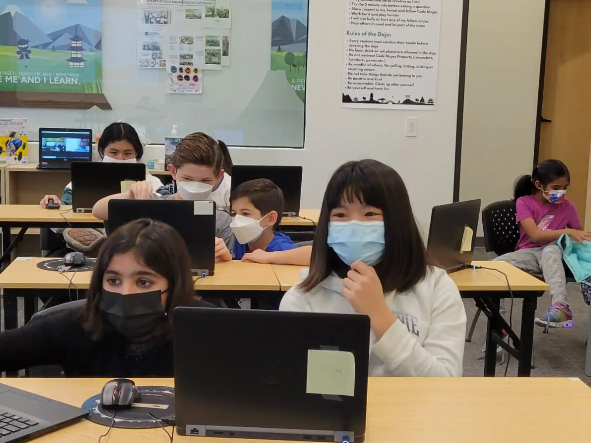 a group of people sitting at desks with laptops