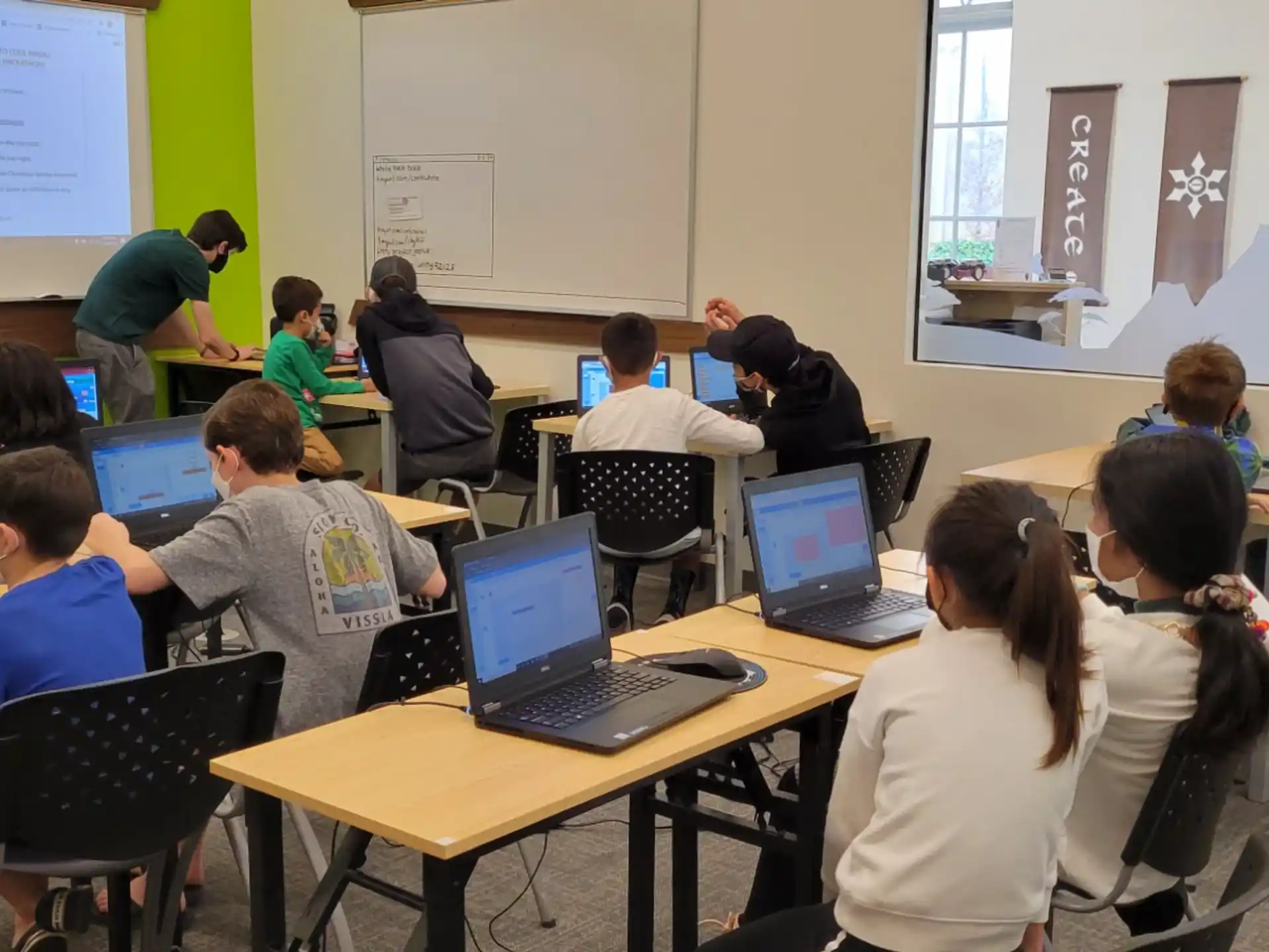 a group of people sitting at tables with laptops