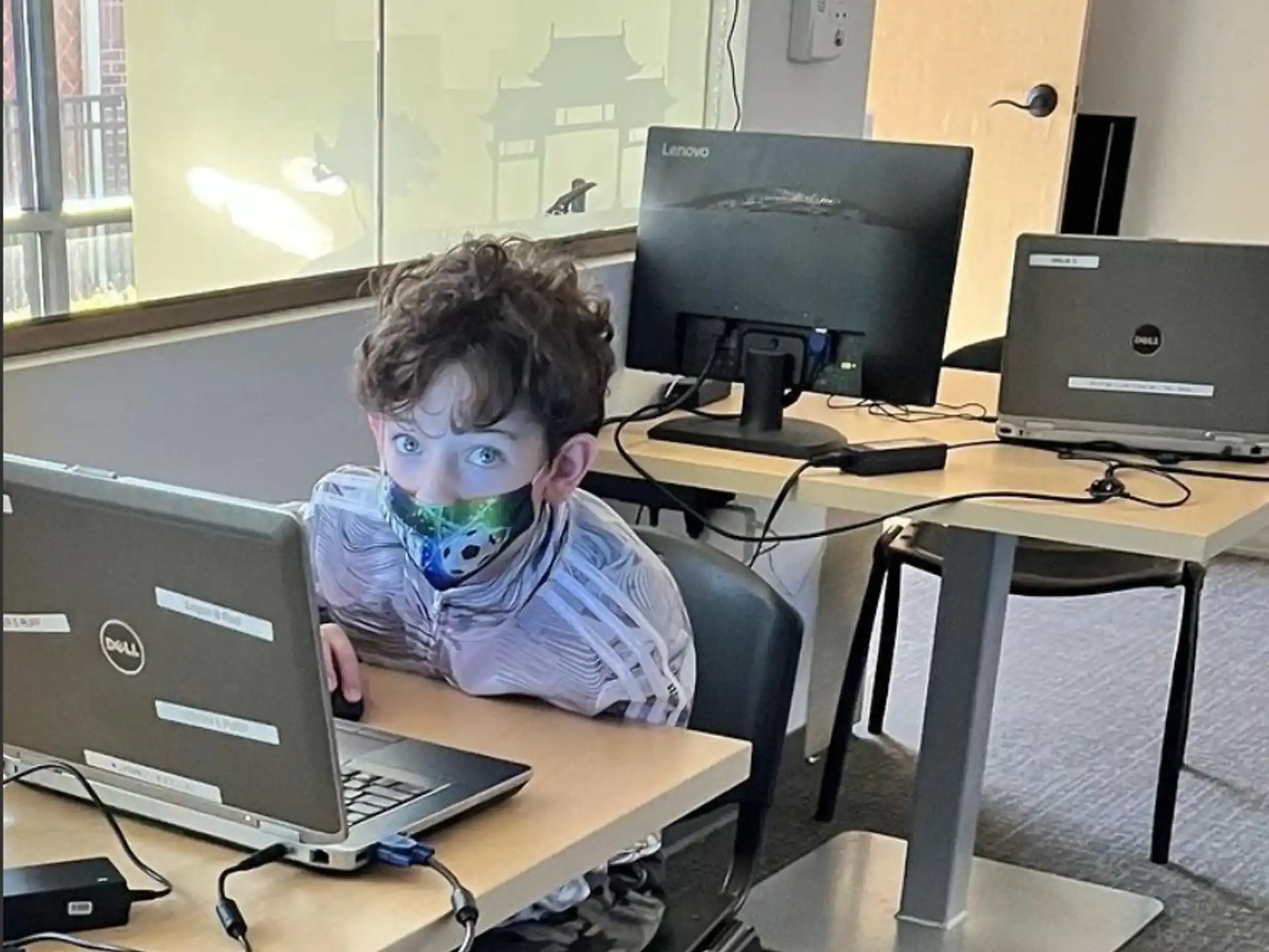 a boy sitting at a desk with a laptop