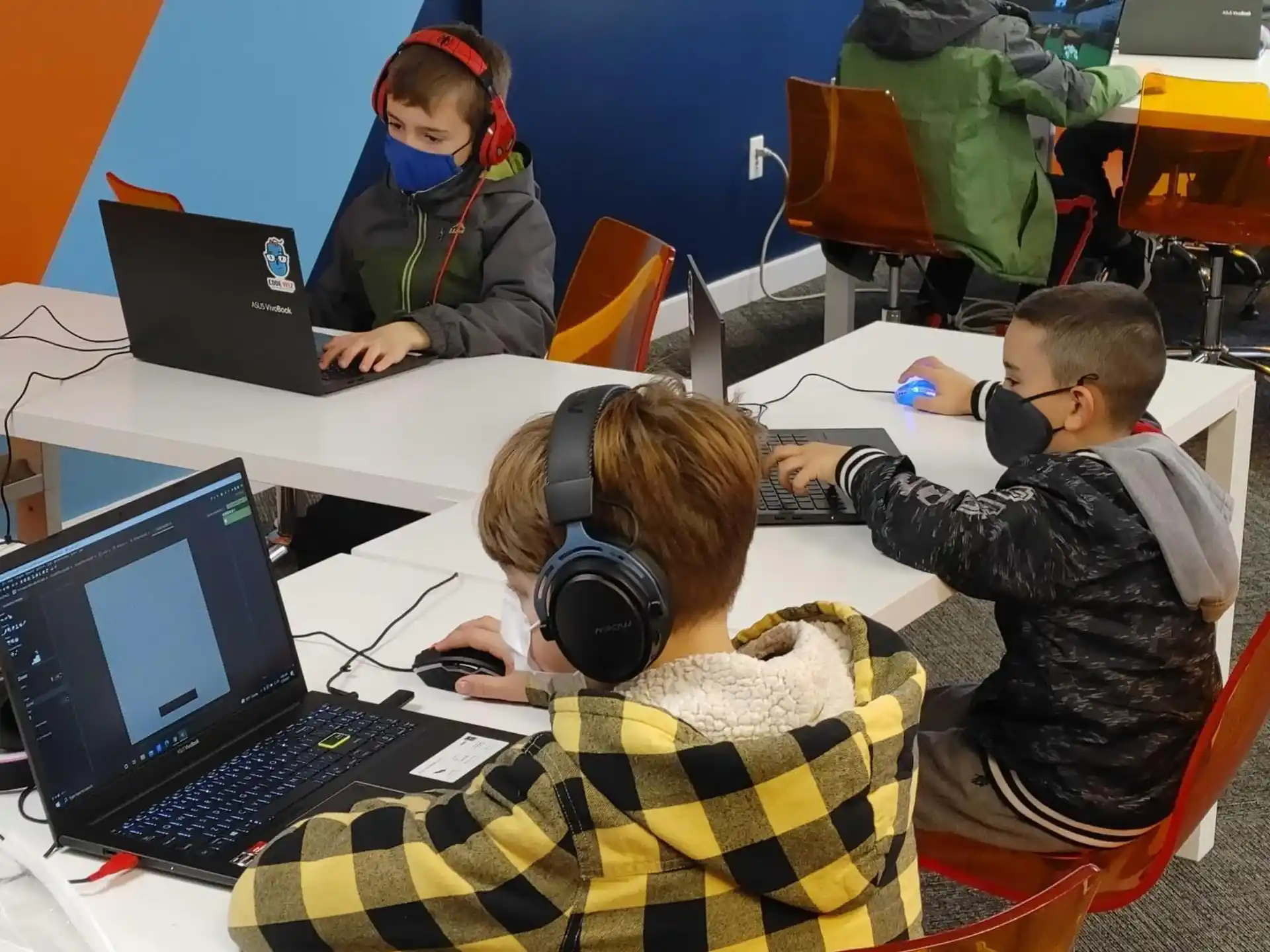 a group of people sitting at a table with laptops