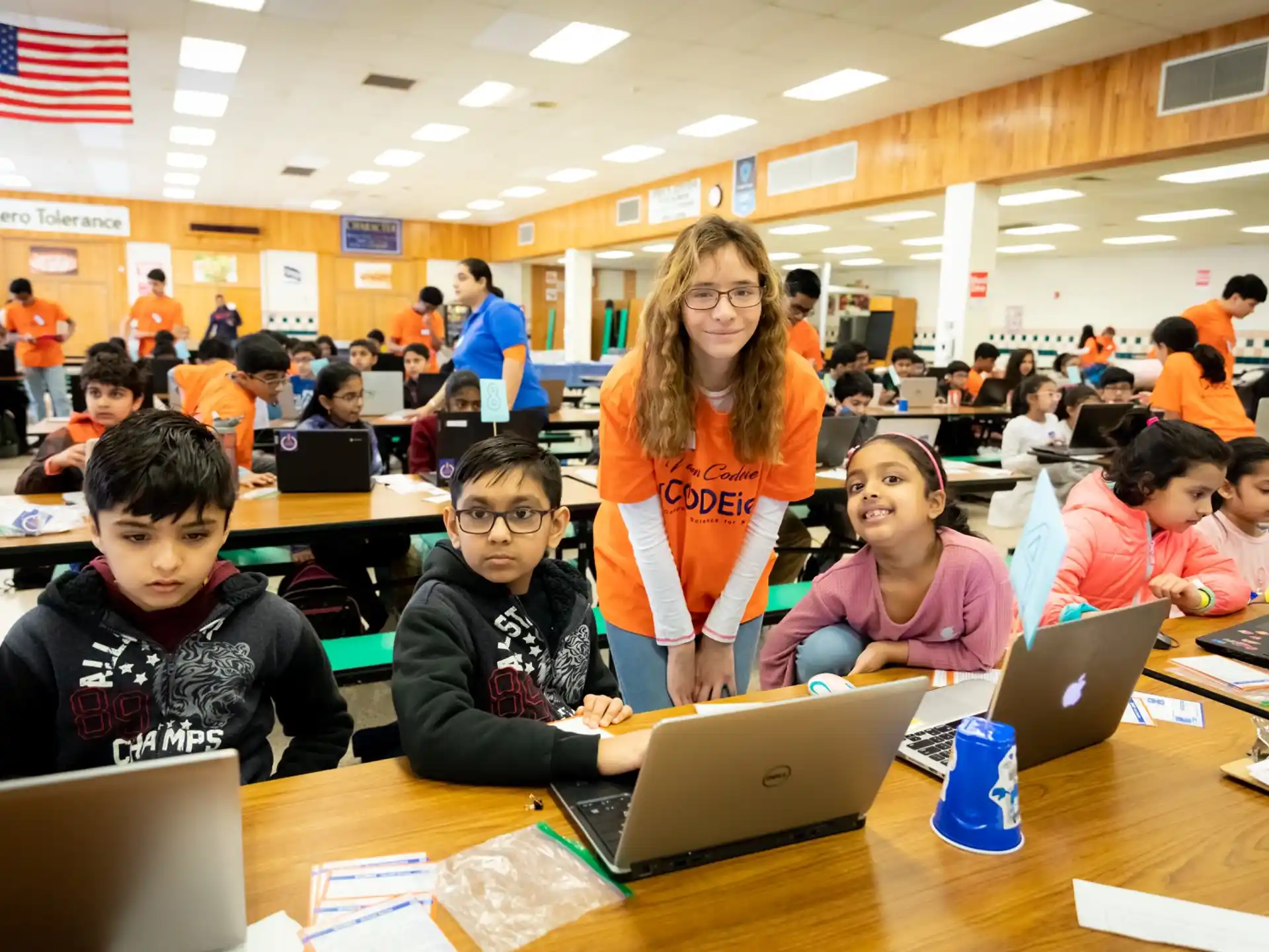 a group of children sitting at desks with laptops