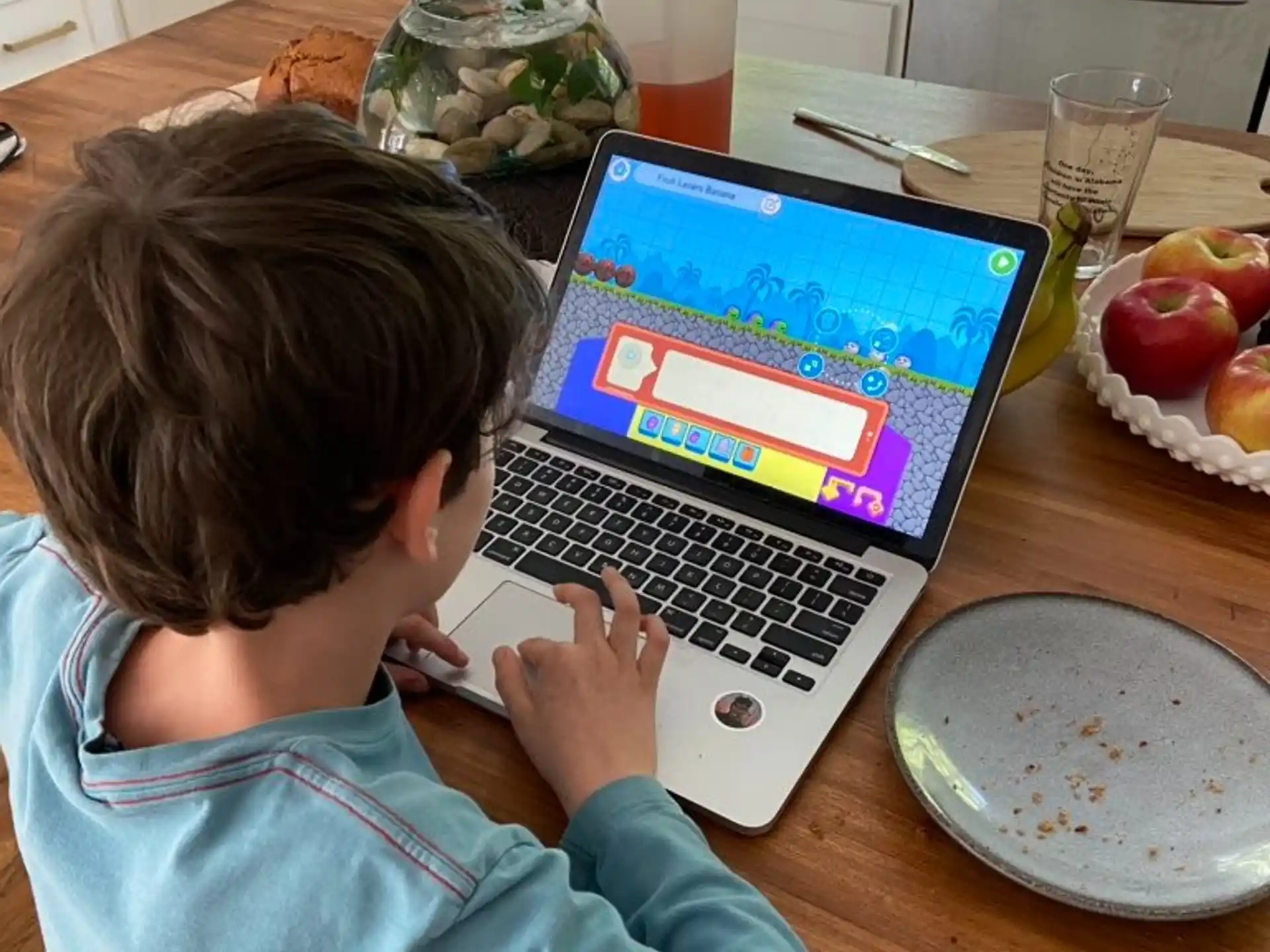 a child sitting at a table with a laptop
