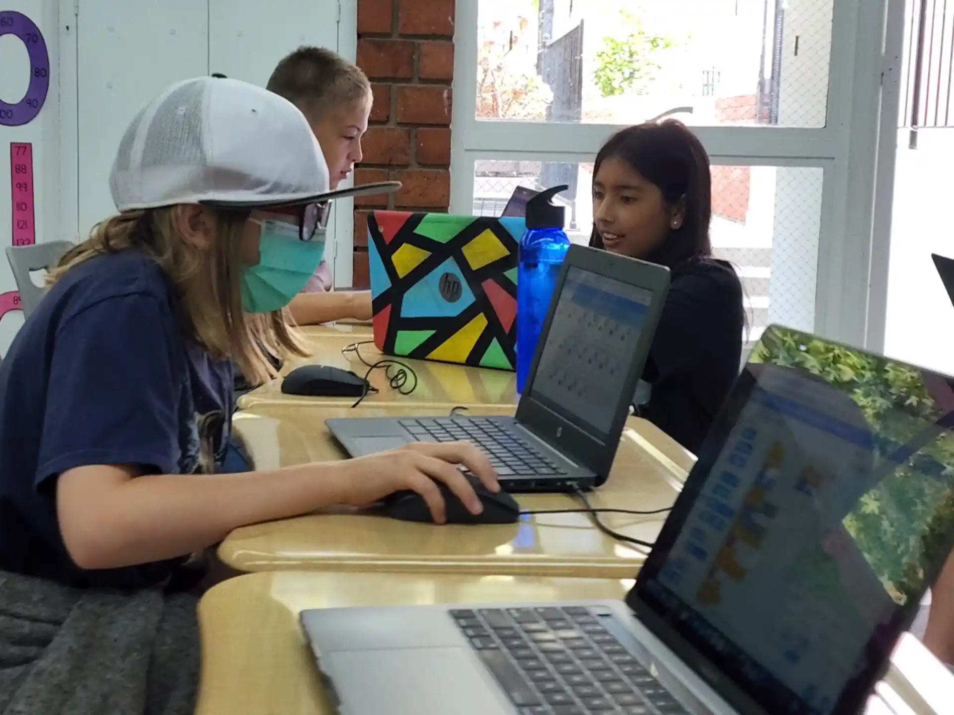 a few people sit around a table with laptops