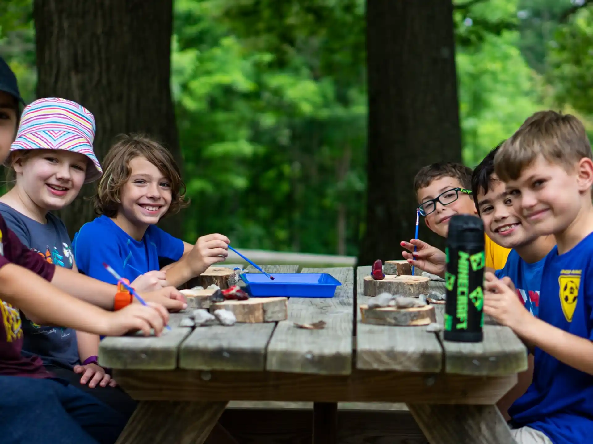 a group of kids sitting at a table with a bottle of beer