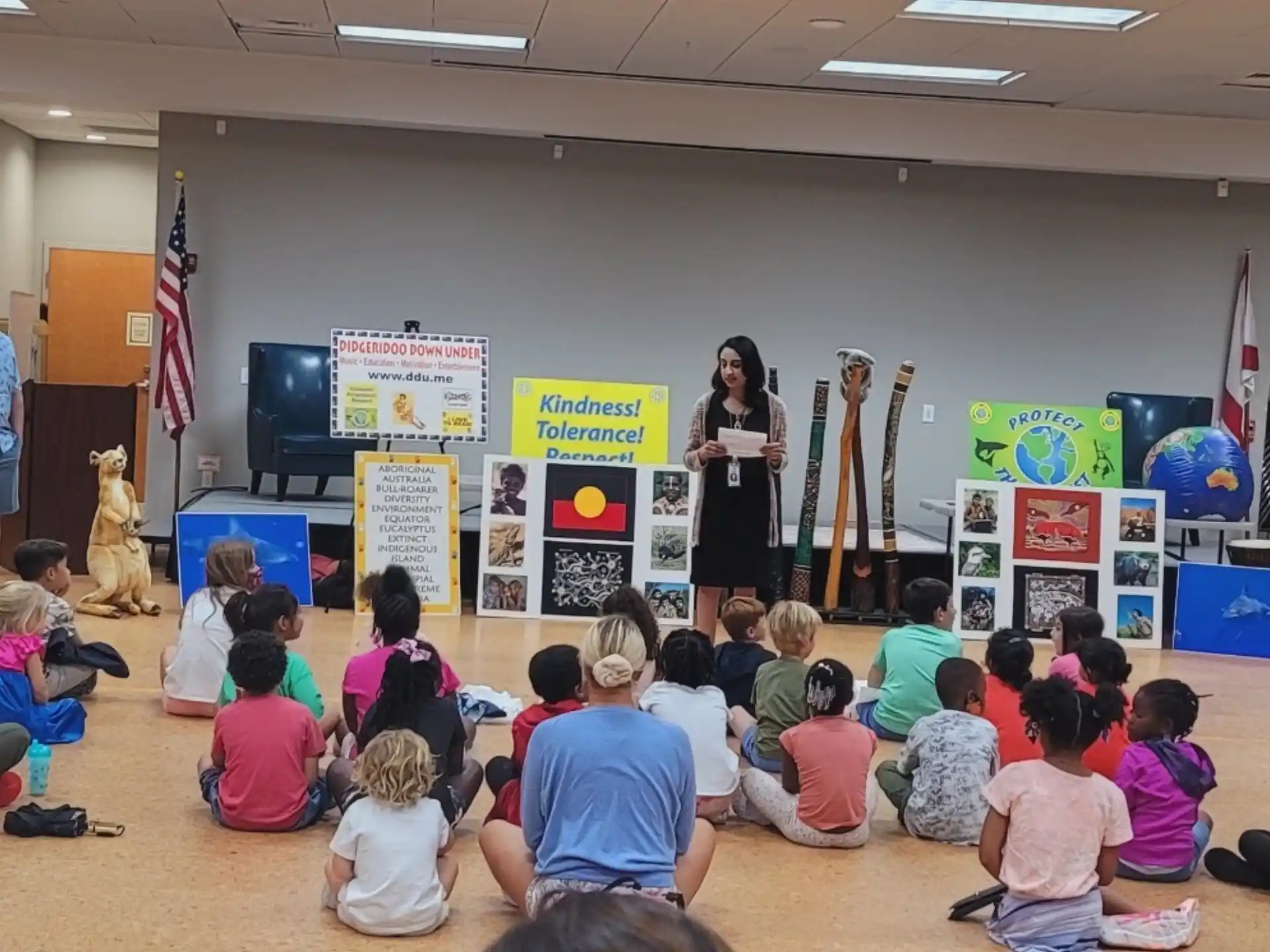 a group of people sitting in a room with a person standing in front of a group of children